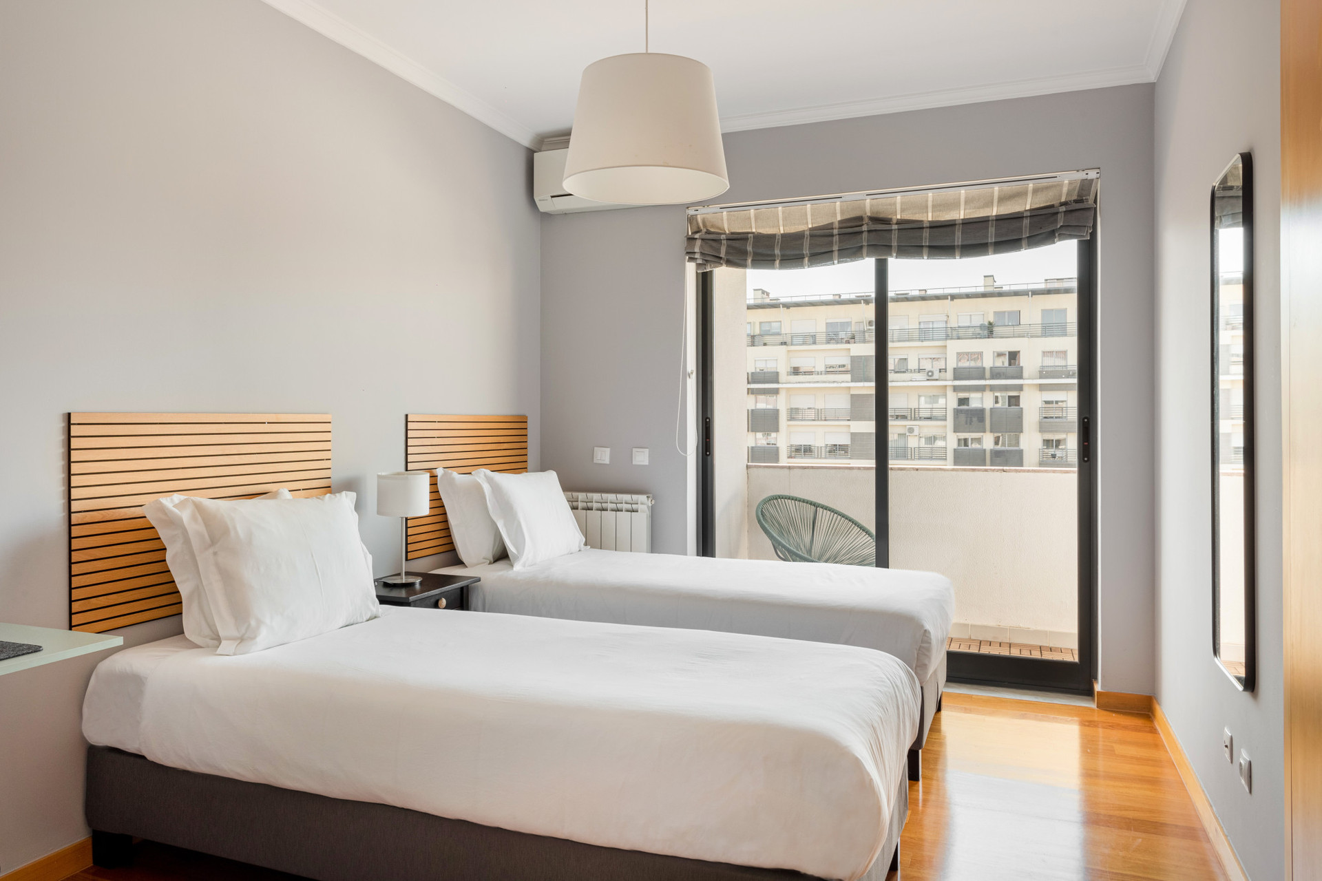 Bedroom with two single beds, AC, built-in closet and dedicated work space with laptop stand and monitor. Enjoy access to the balcony