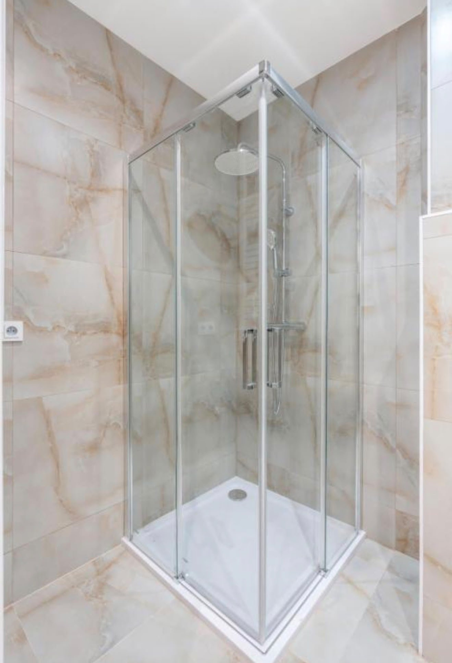 Glass shower enclosure marble tiles