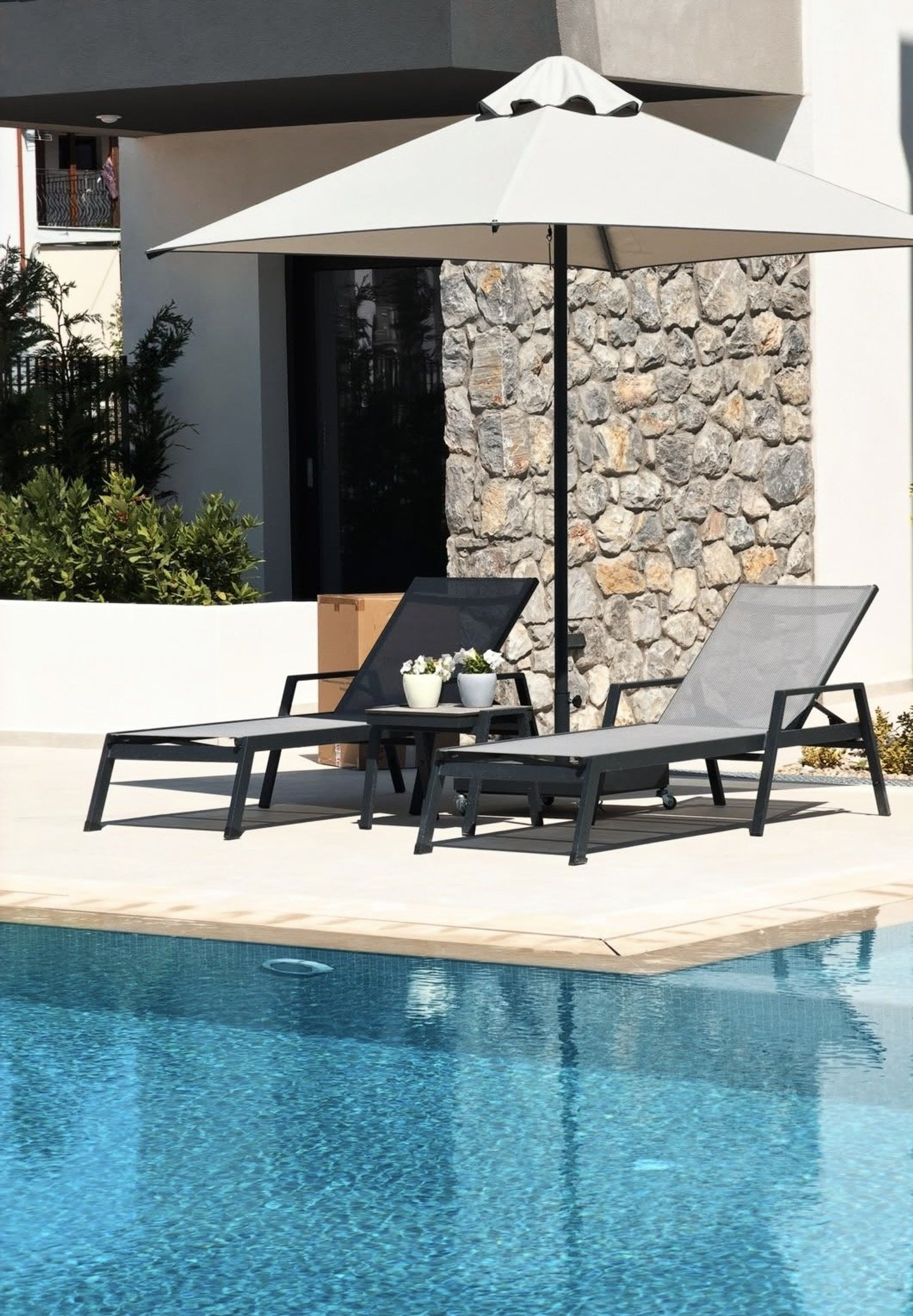 Pool loungers with umbrella and stonework