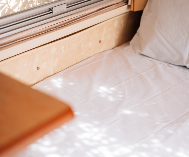 Bed beside sunlit window