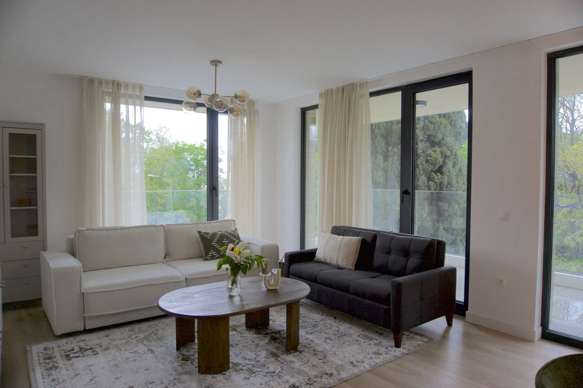 Step into a bright, sun-drenched living area surrounded by floor-to-ceiling windows and peaceful, leafy views. This open, modern space is designed for ultimate relaxation after a day at the nearby beaches or thermal springs. Hosting extra guests? Both the elegant cream sofa and the stylish charcoal sofa easily convert into comfortable beds, offering flexible sleeping arrangements.
