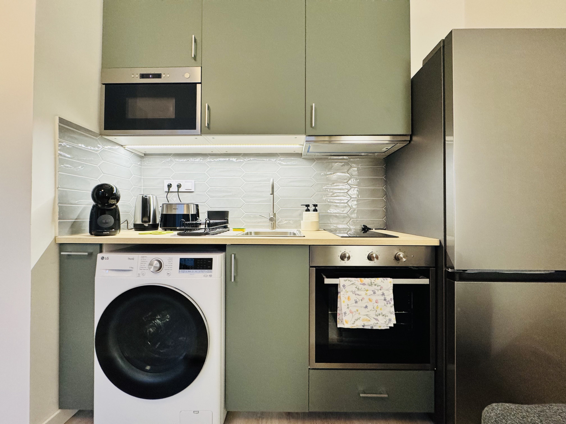Green kitchen with washer and oven