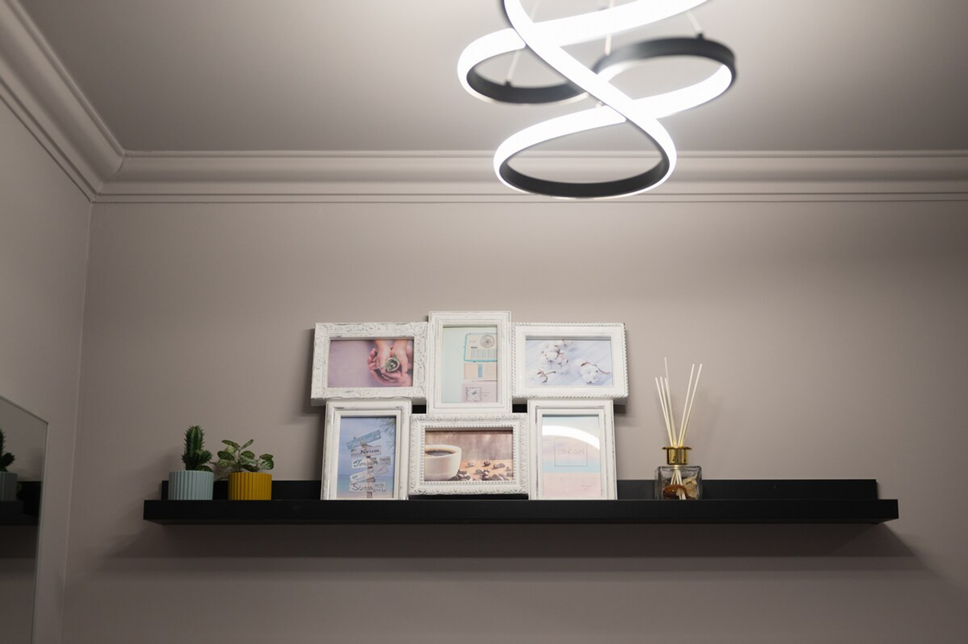 A stylish floating shelf with elegant decor, family photos, and a modern ceiling light, creating a cozy atmosphere.