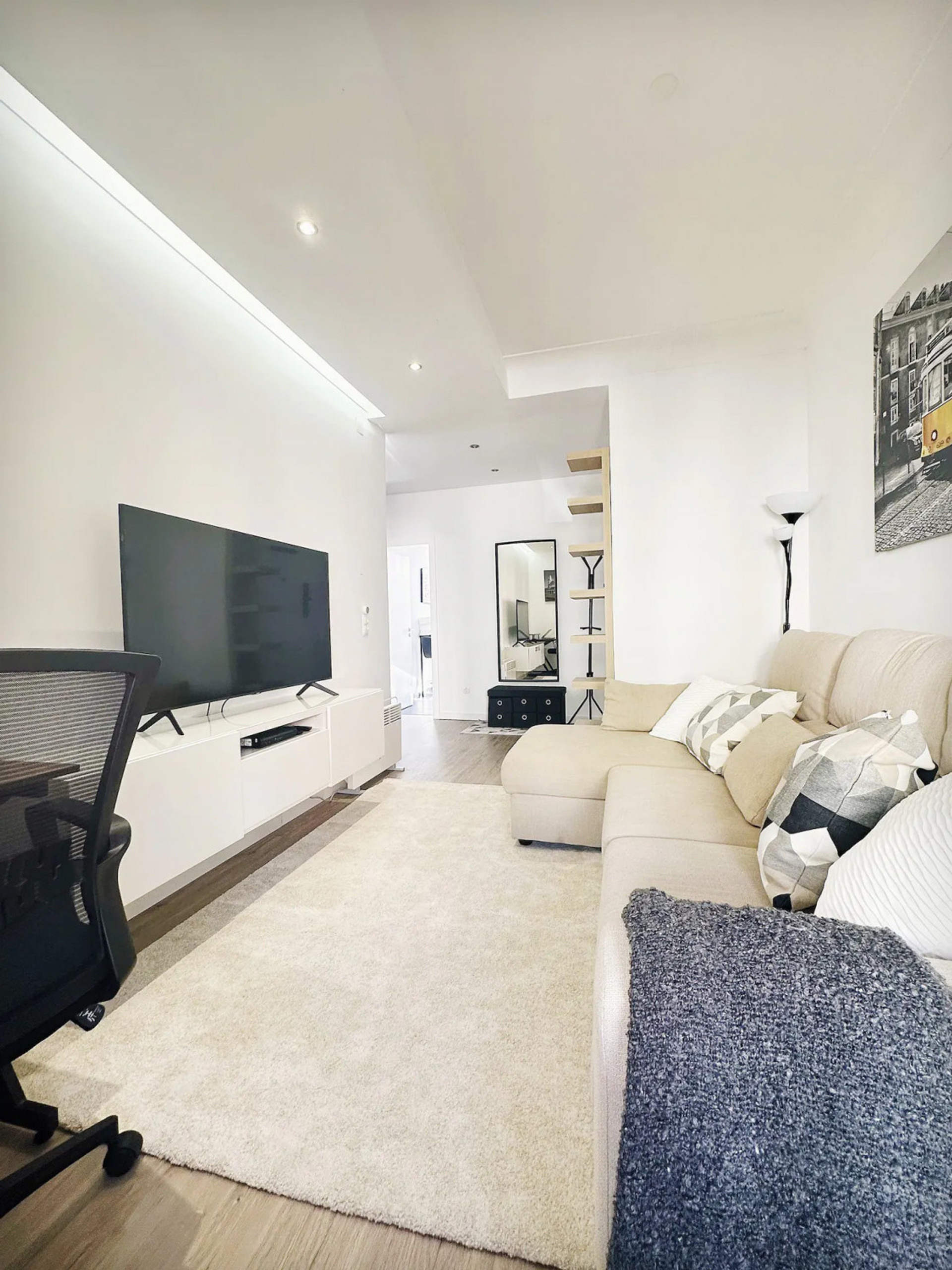 This inviting living room features a large TV with 150+ channels, a comfy sofa, cozy pillows, warm blanket, and a desk for work