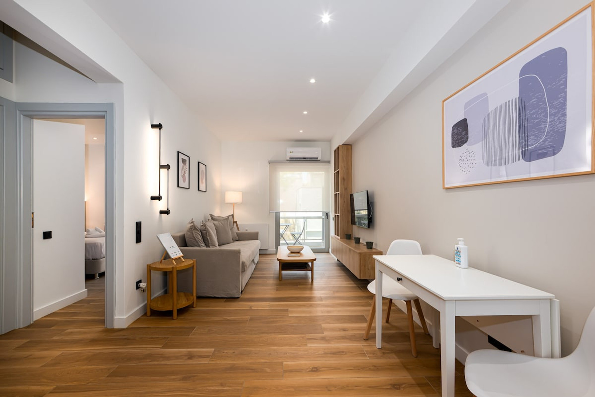 Bright and inviting open-plan space with modern décor, warm wooden floors, and tasteful artwork. Features a cosy seating area, stylish dining table, and ample natural light for a comfortable and relaxing stay. Perfect for unwinding or entertaining!
