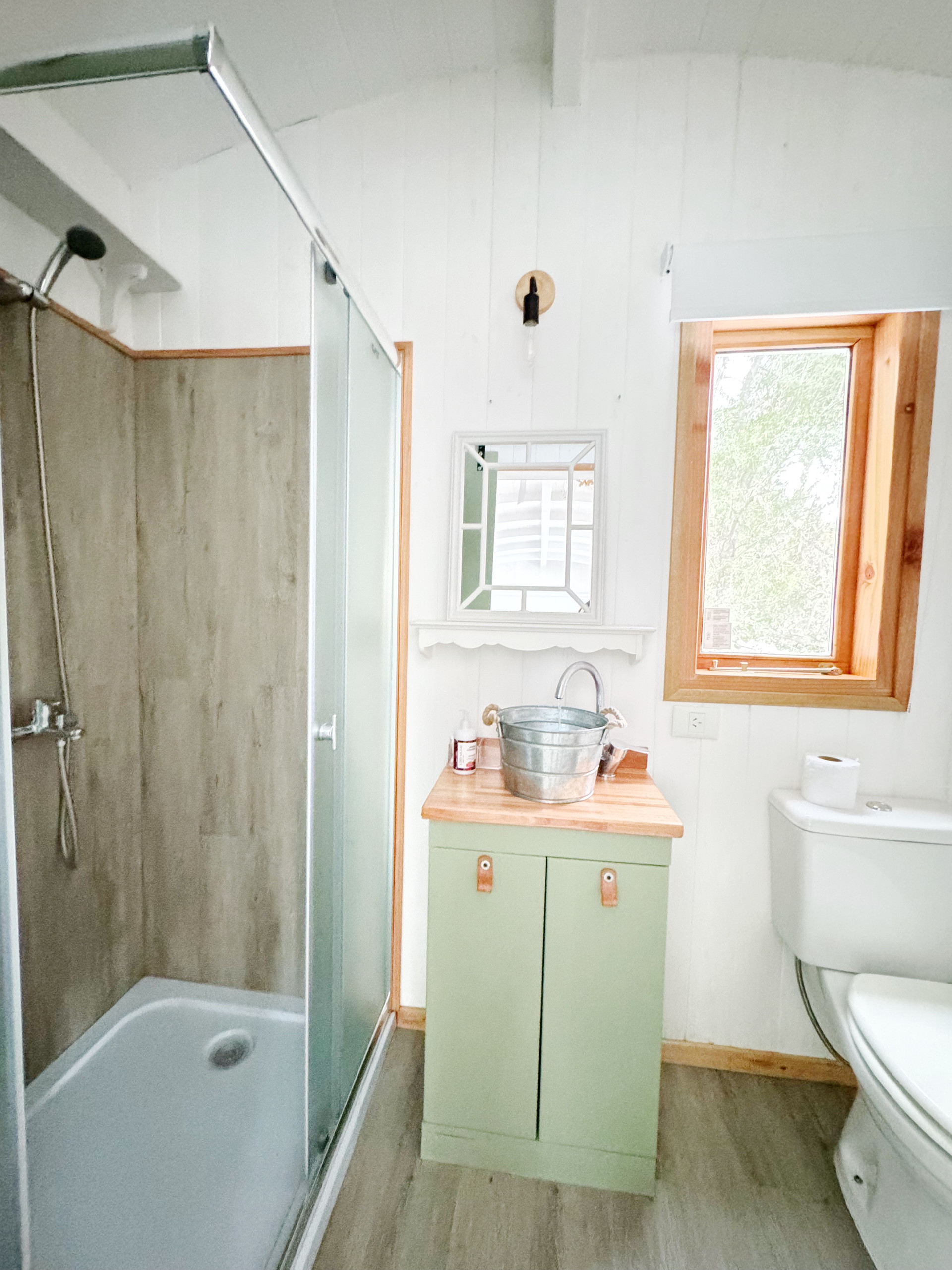 Baño con ducha amplia y terminaciones en madera. Incluye toallas y amenities básicos, diseñado para uso diario cómodo.