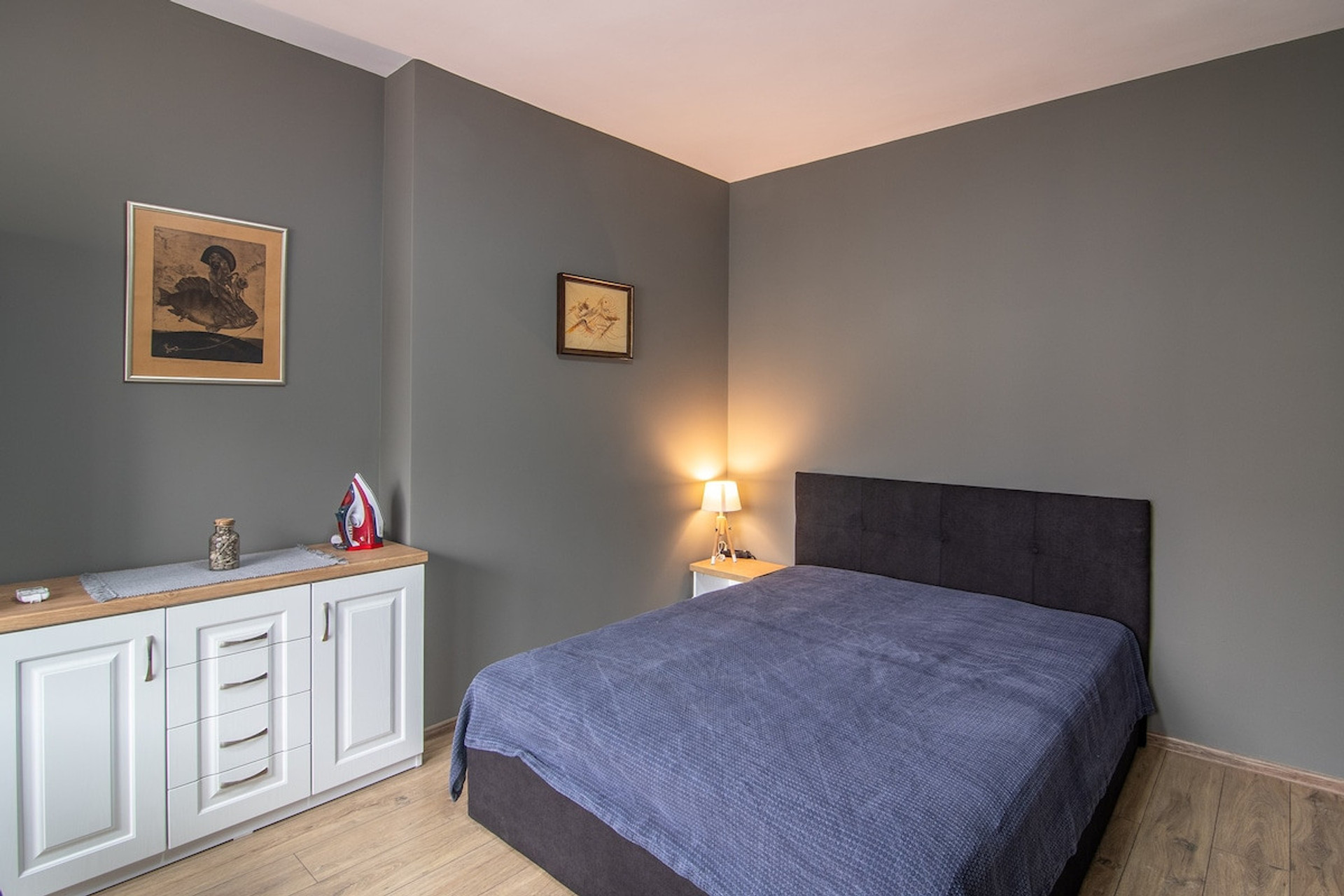 Cozy bedroom with modern design – A stylish retreat featuring a comfortable bed, soft lighting, and elegant dark walls. Large windows bring in natural light, creating a relaxing atmosphere for a restful night’s sleep.