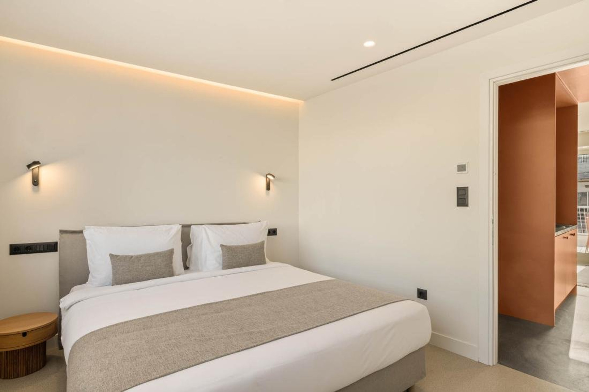Bright bedroom with orange kitchen glimpse