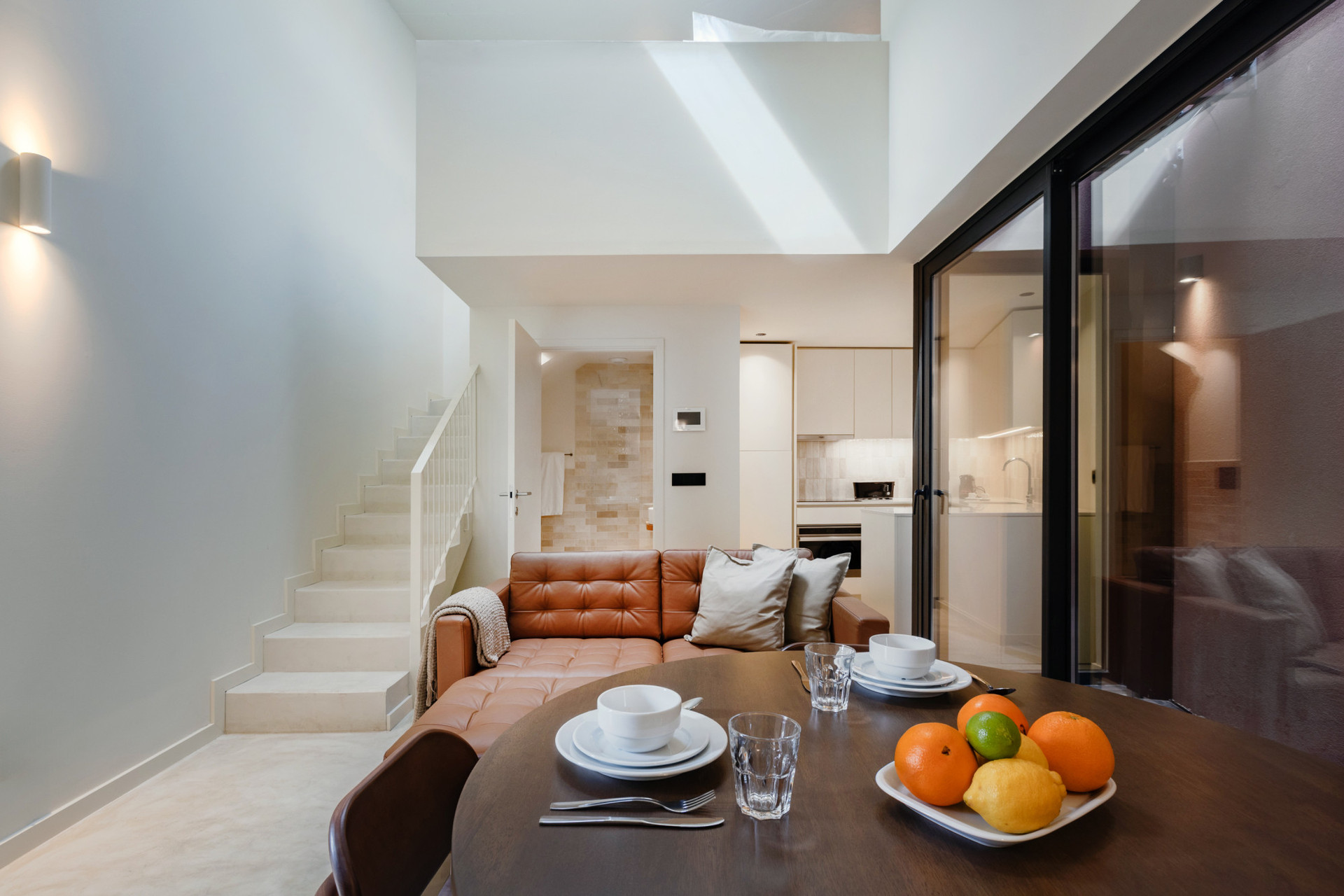 Simple, yet comfortable living area with AC, an elegant leather sofa, TV and dining table (that doubles as a working space). Staircase to the mezzanine bedroom.