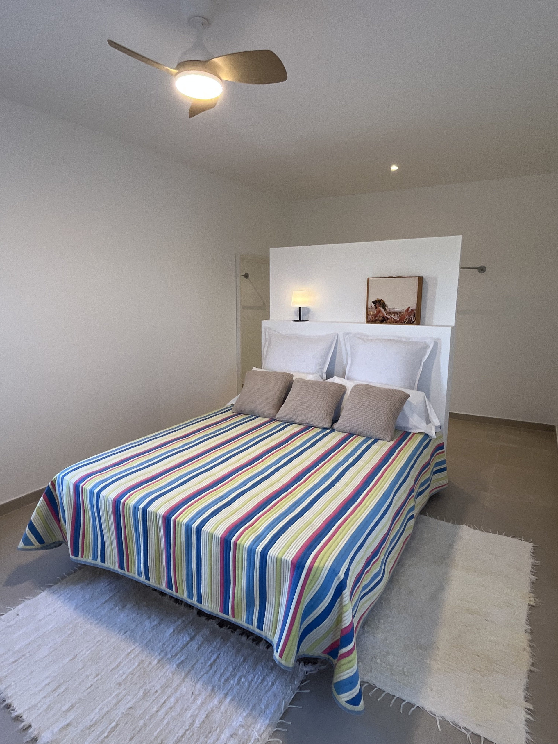 Bedroom with striped bedding ceiling fan