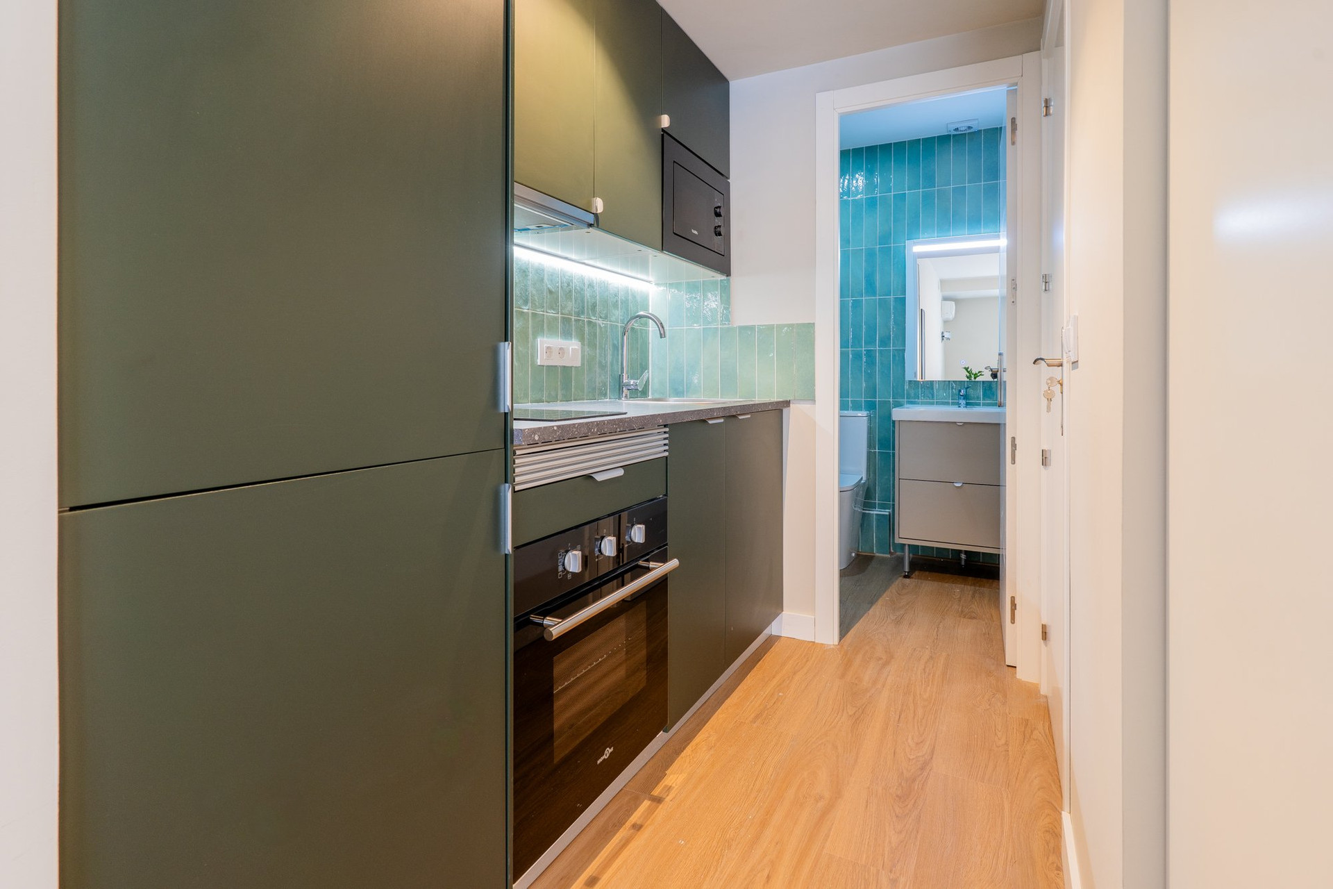 Dark green kitchen with bathroom view