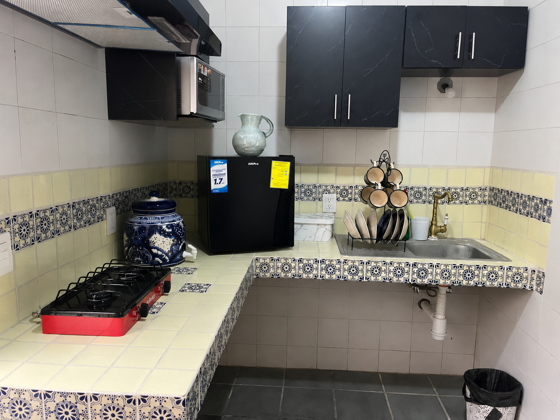 Equipped kitchenette with stove, mini fridge, microwave, sink and basic utensils for temporary stays. Cocina equipada con parrilla, frigobar, microondas, tarja y utensilios básicos para estancias temporales.
