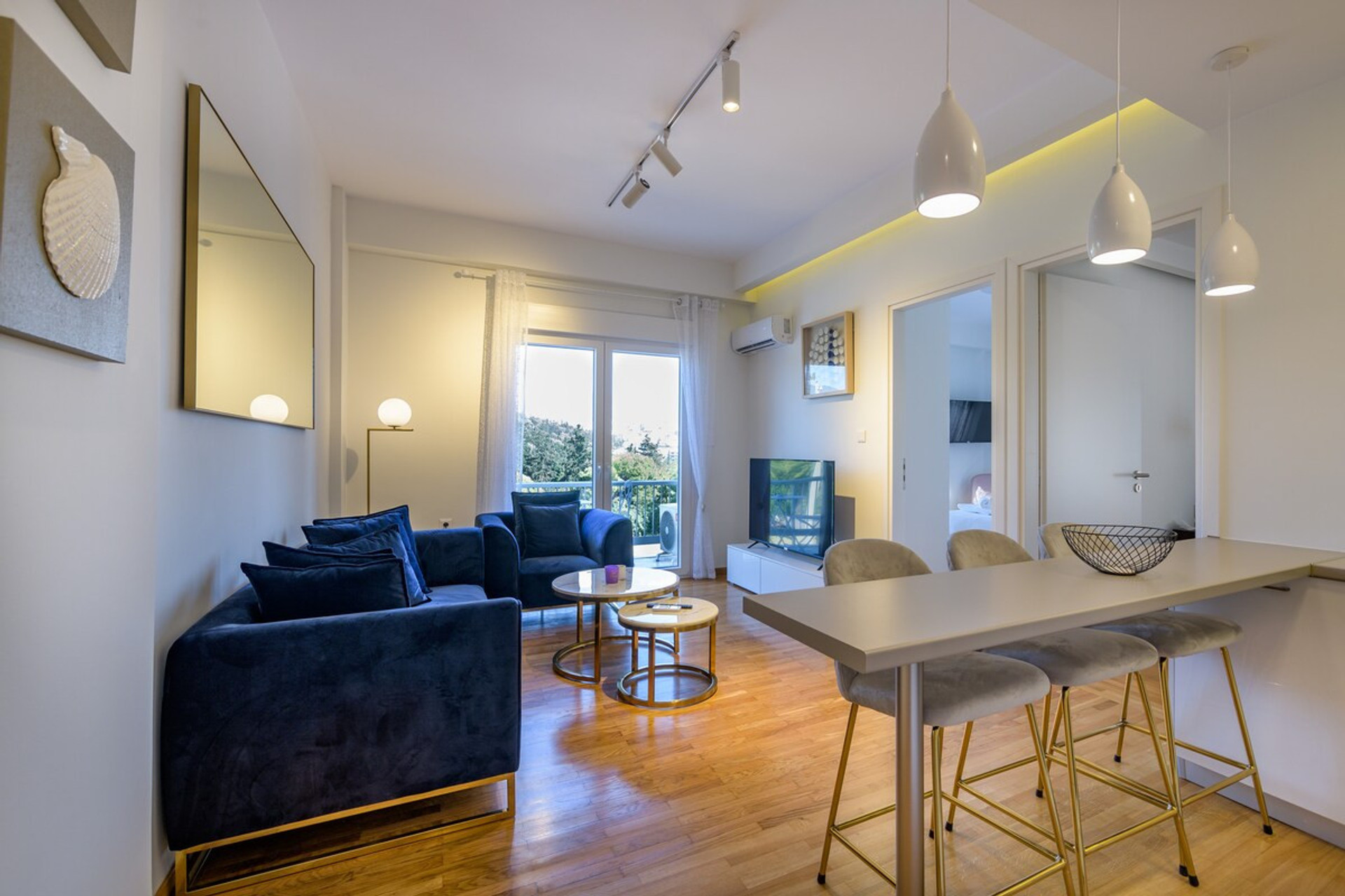 Bright and stylish living space with cosy navy sofas, sleek lighting, and a modern open-plan design. Enjoy natural light streaming through large windows, creating a warm and inviting atmosphere perfect for relaxation or socialising.