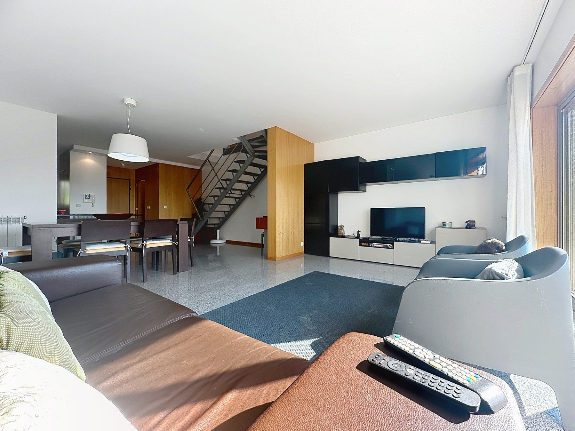 Bright living room with staircase and TV