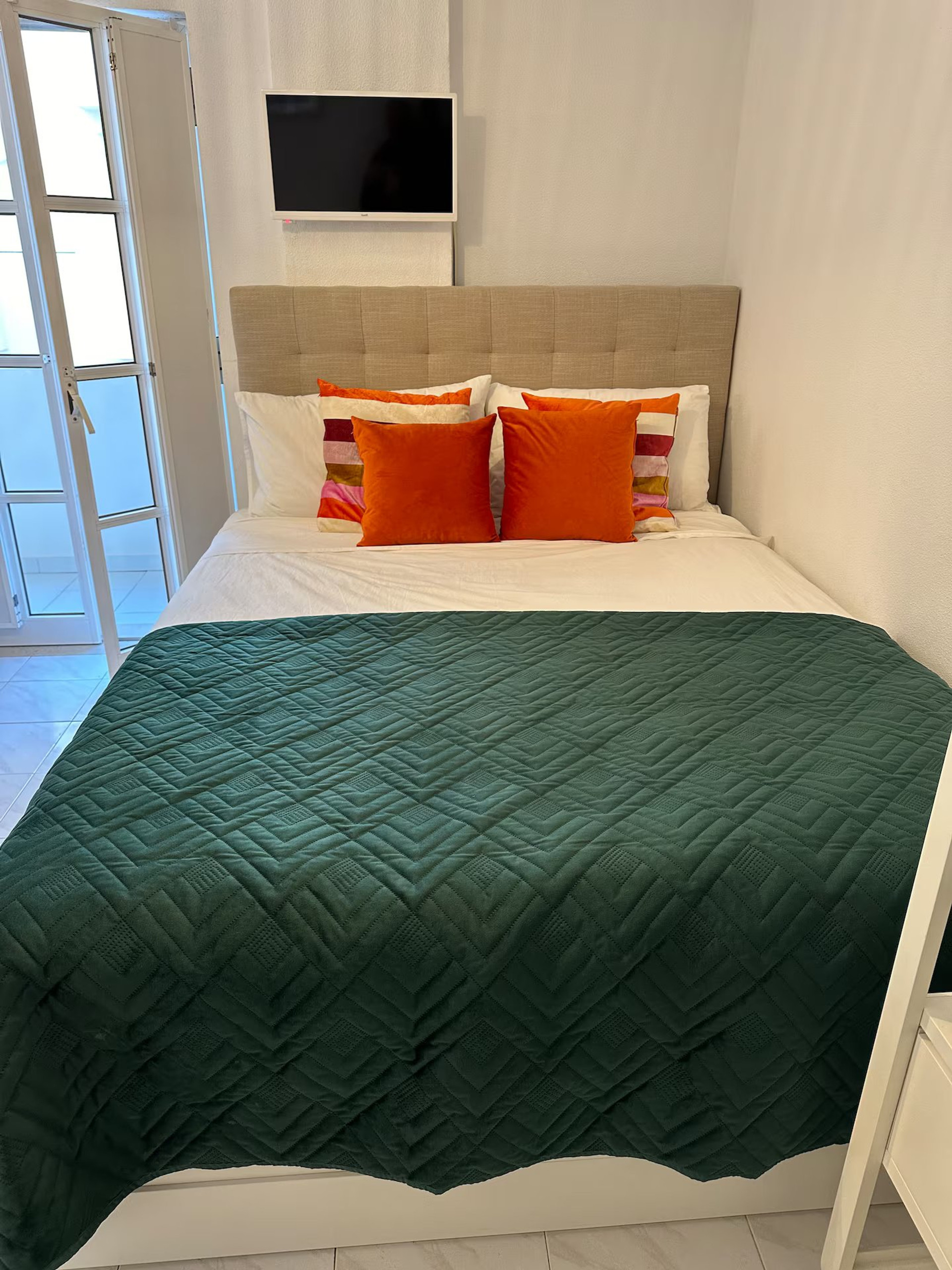 Bed with TV and orange pillows