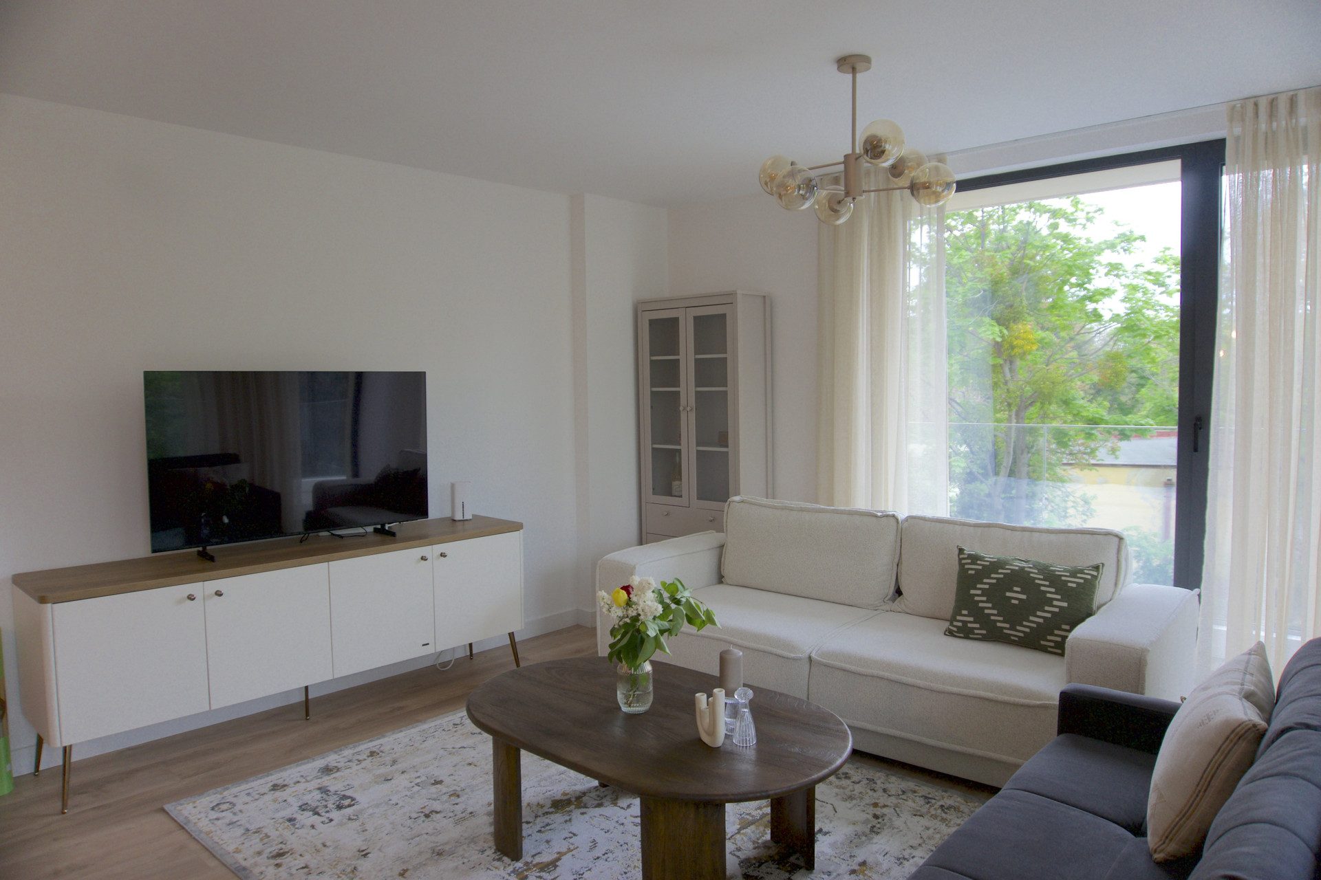 Enjoy cozy movie nights or catch up on the news with the large flat-screen TV and sleek media console. The thoughtful layout provides plenty of space to unwind, while the minimalist design and natural light create a calming environment—perfect whether you're kicking back on the sofa or taking a quick remote work call.