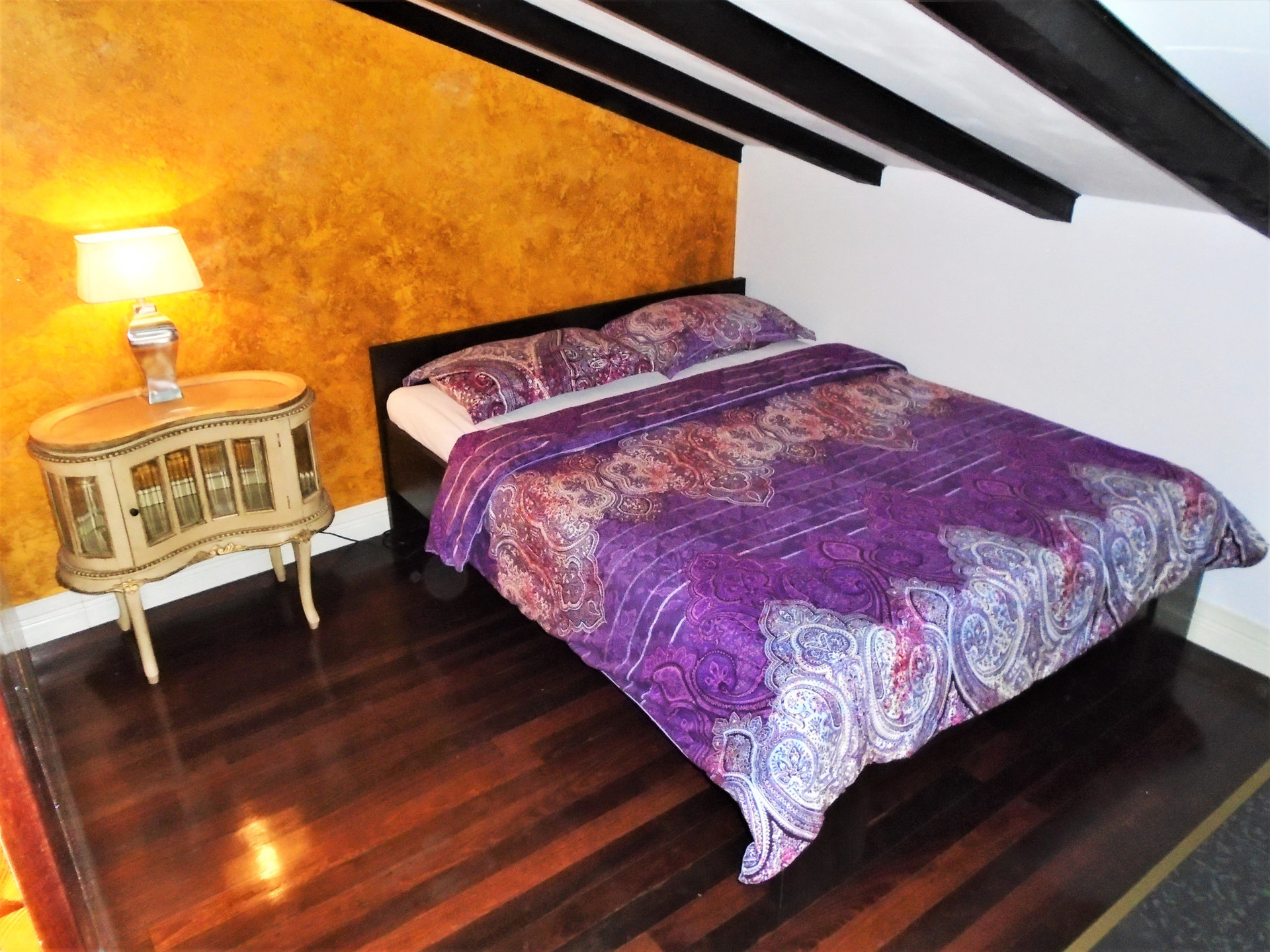 Bedroom with purple bedding golden wall