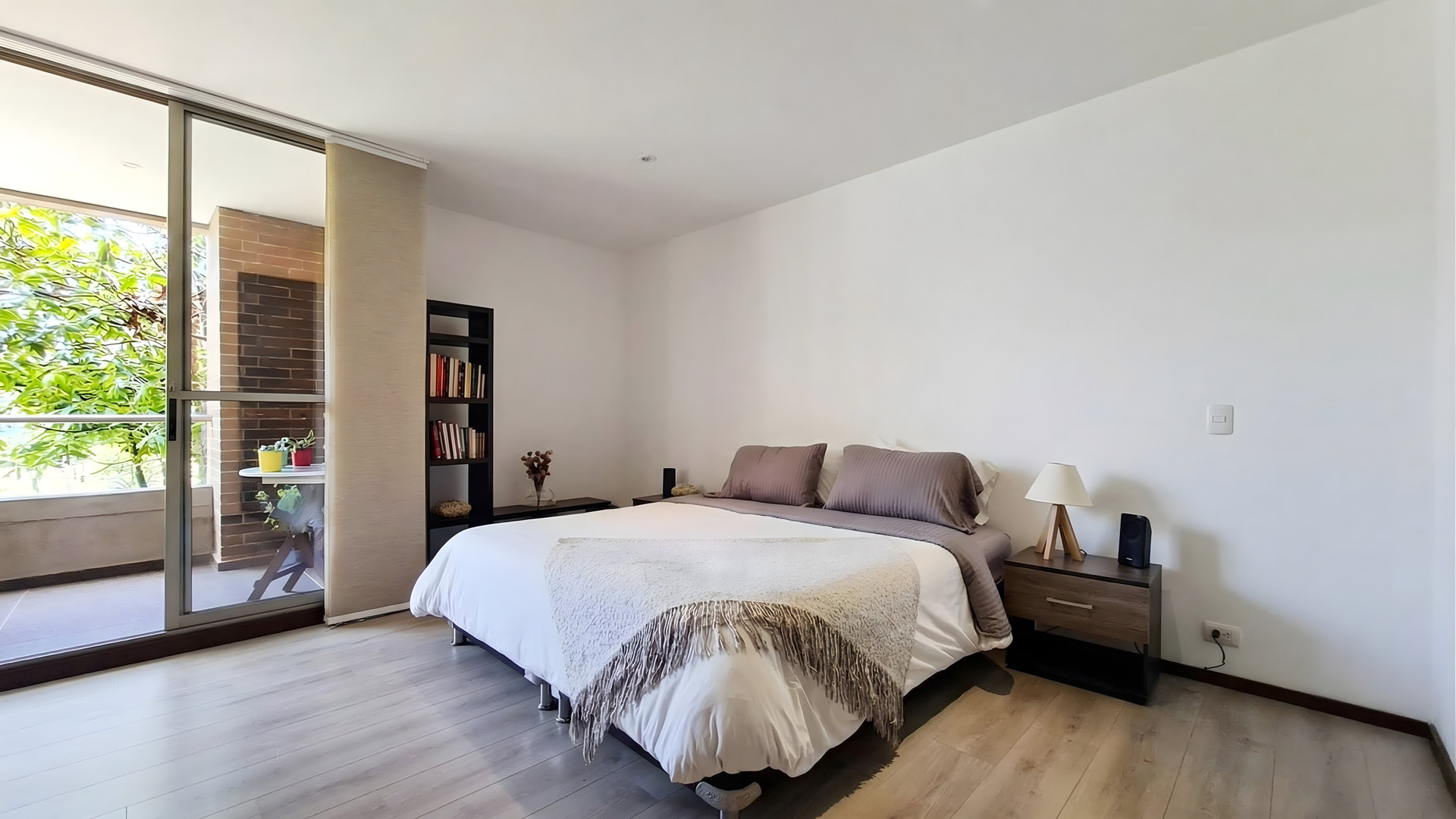 Spacious and quiet bedroom with a comfortable bed, natural light and direct access to the balcony.