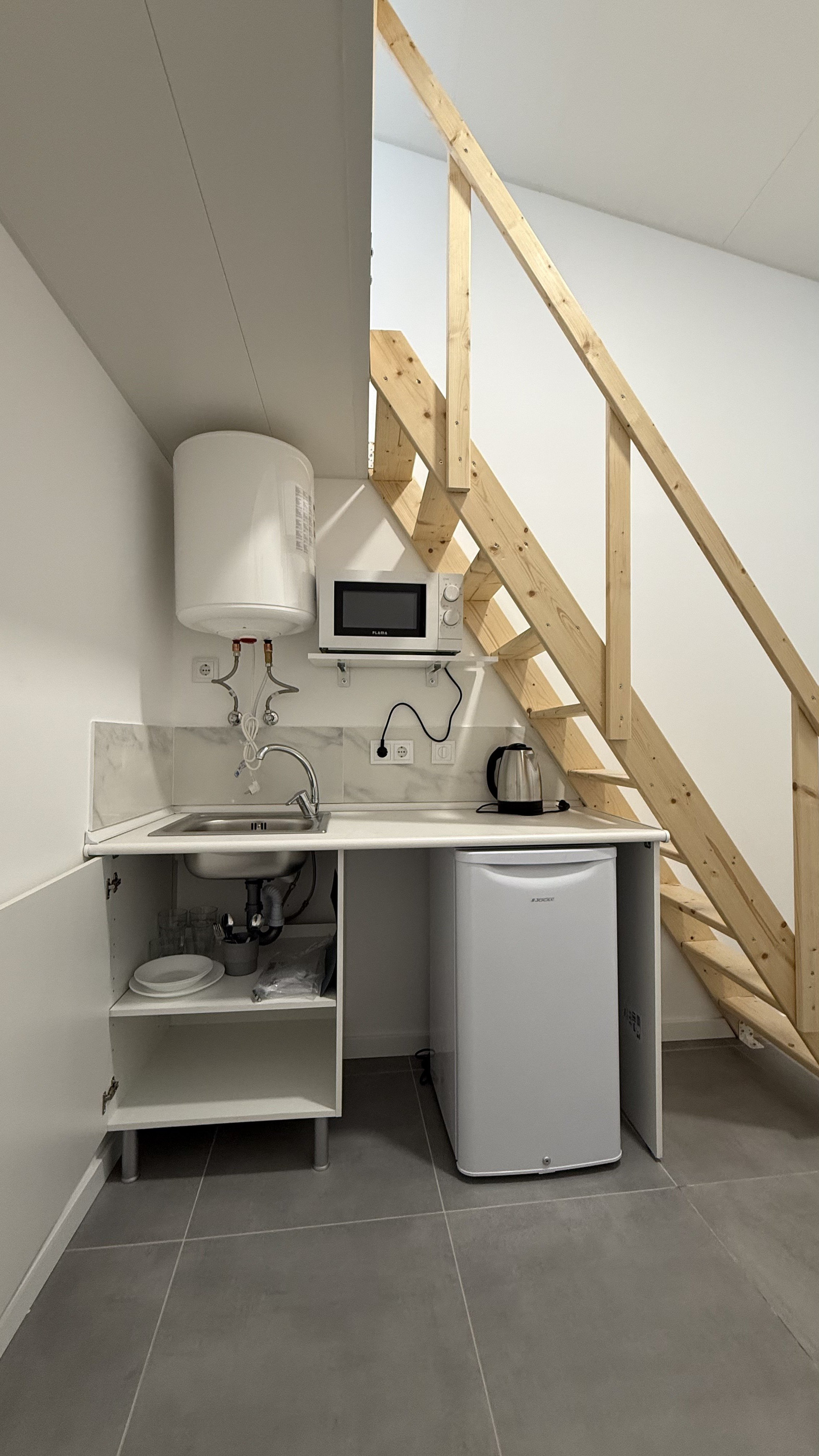 Kitchenette with fridge under stairs