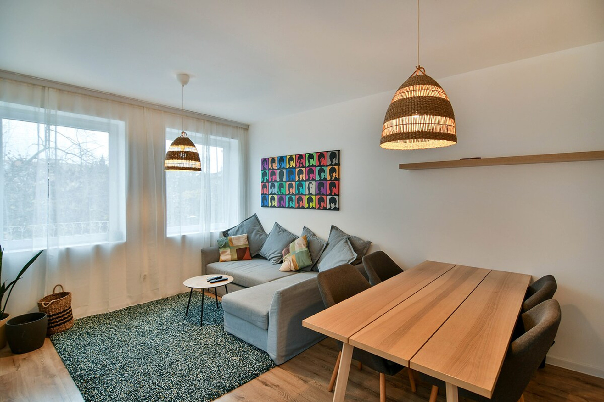 A stylish and cozy living area filled with natural light, featuring a comfortable sofa, a wooden dining table, and warm decorative elements, making it the perfect place to relax after a long day in the city.