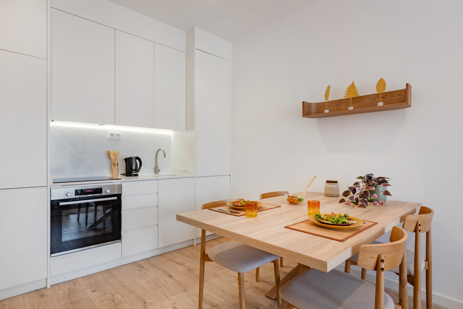 Fully equipped kitchen with washing machine and a modern wooden dining table.
