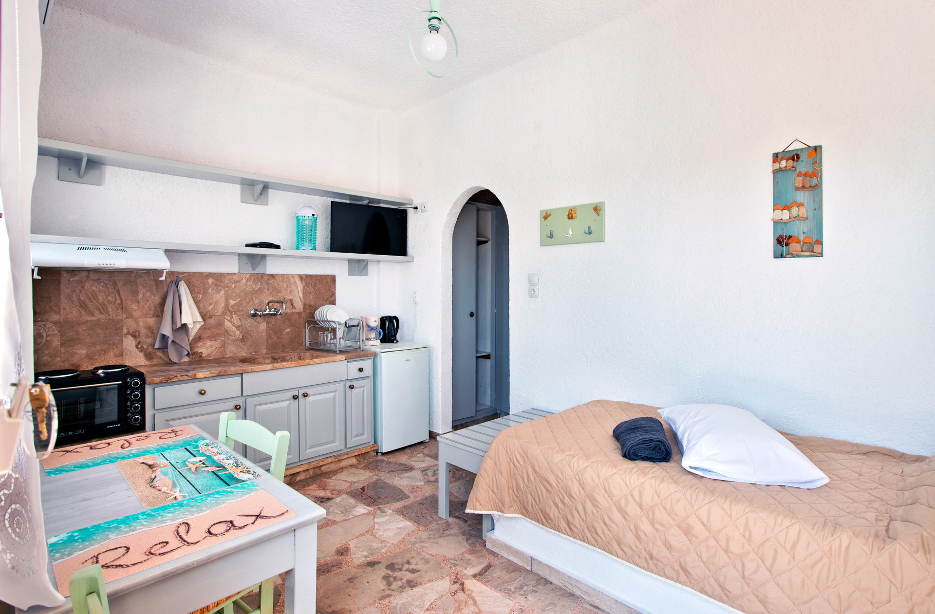 View of the living room, kitchenette, sofa bed, table with chairs and entrance to the hallway with wardrobe