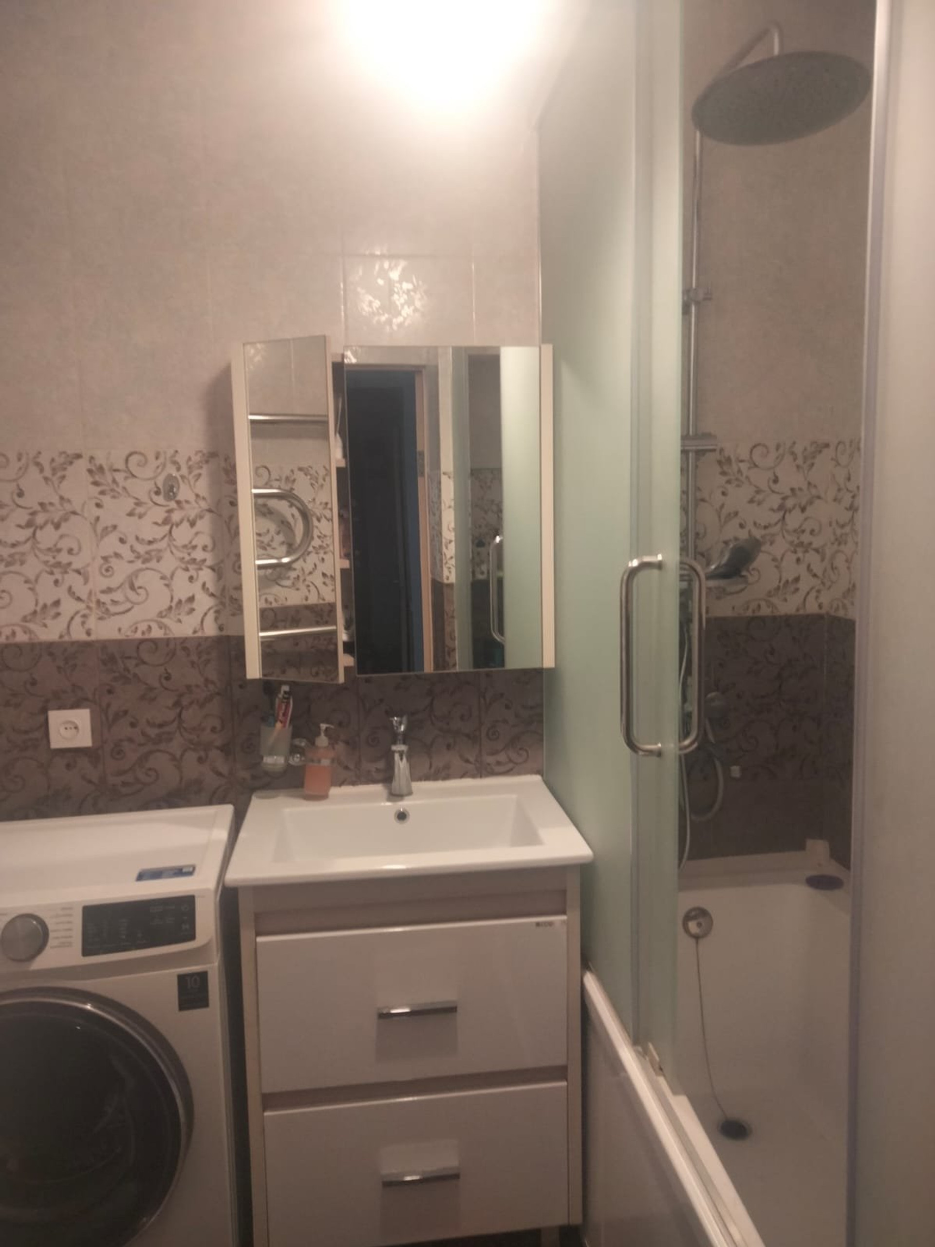 Modern bathroom with washing machine, walk-in shower and essential toiletries.