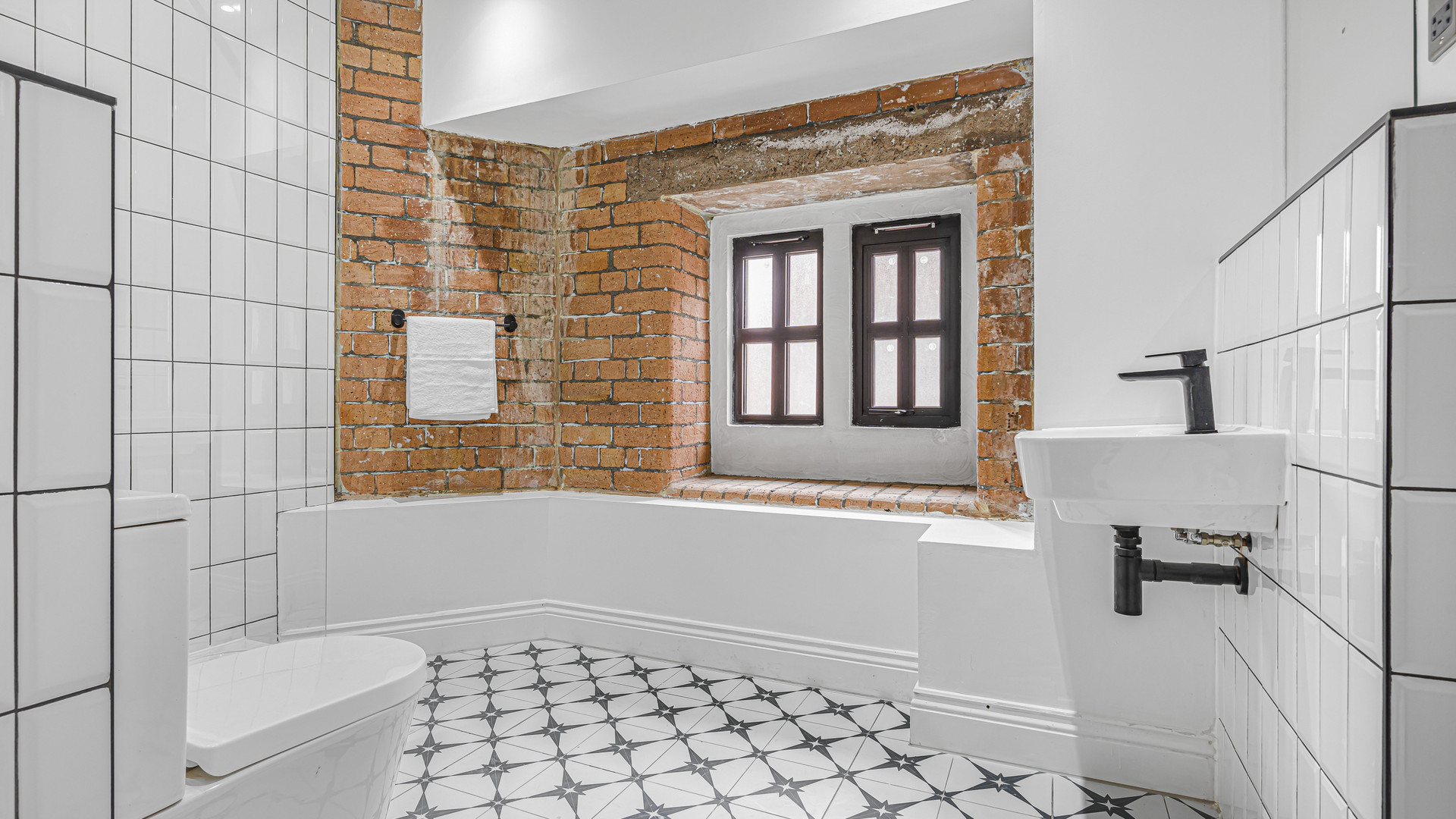 Bathroom with bathtub brick wall window
