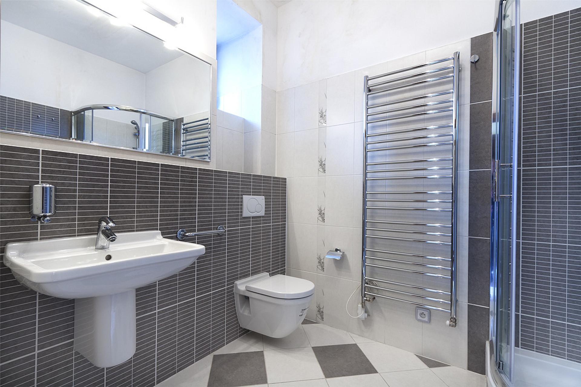 A bathroom with standing shower, toilet and heating ladder
