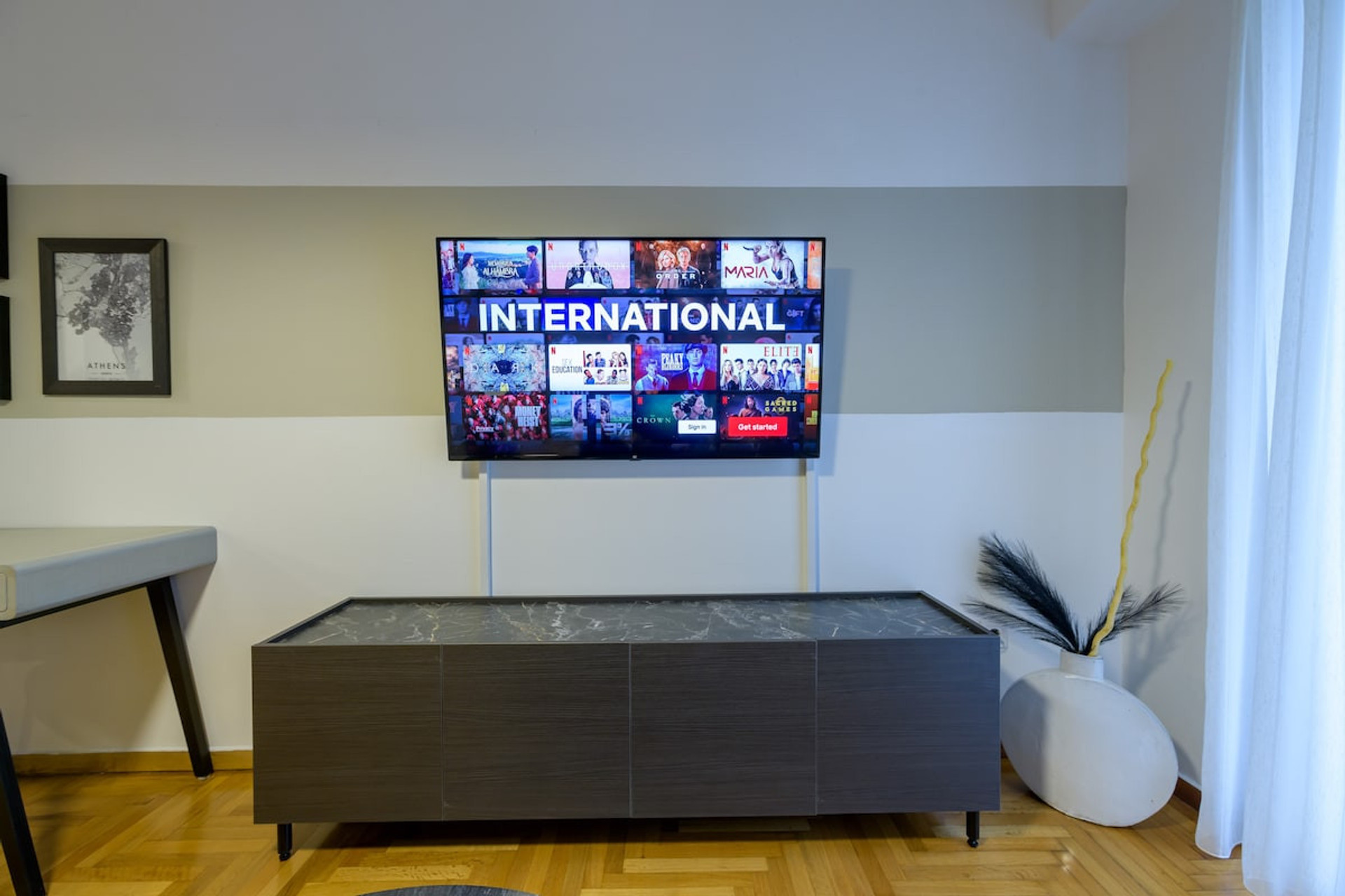 Elegant living space featuring a sleek smart TV on a stylish console, perfect for unwinding with international entertainment. The room's contemporary decor and soft lighting create a warm and inviting atmosphere, ideal for relaxation and leisure.