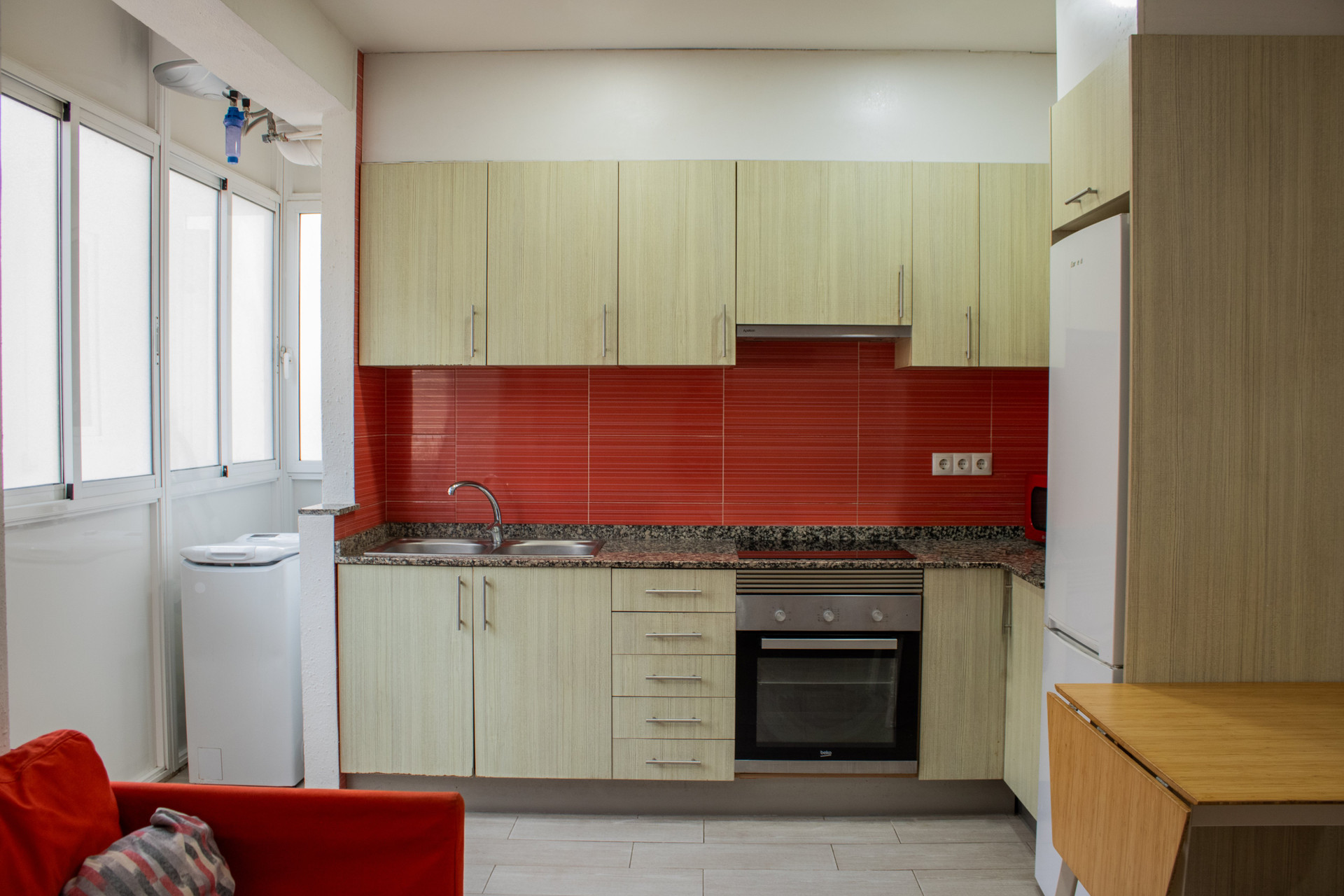Kitchen with red backsplash and laundry