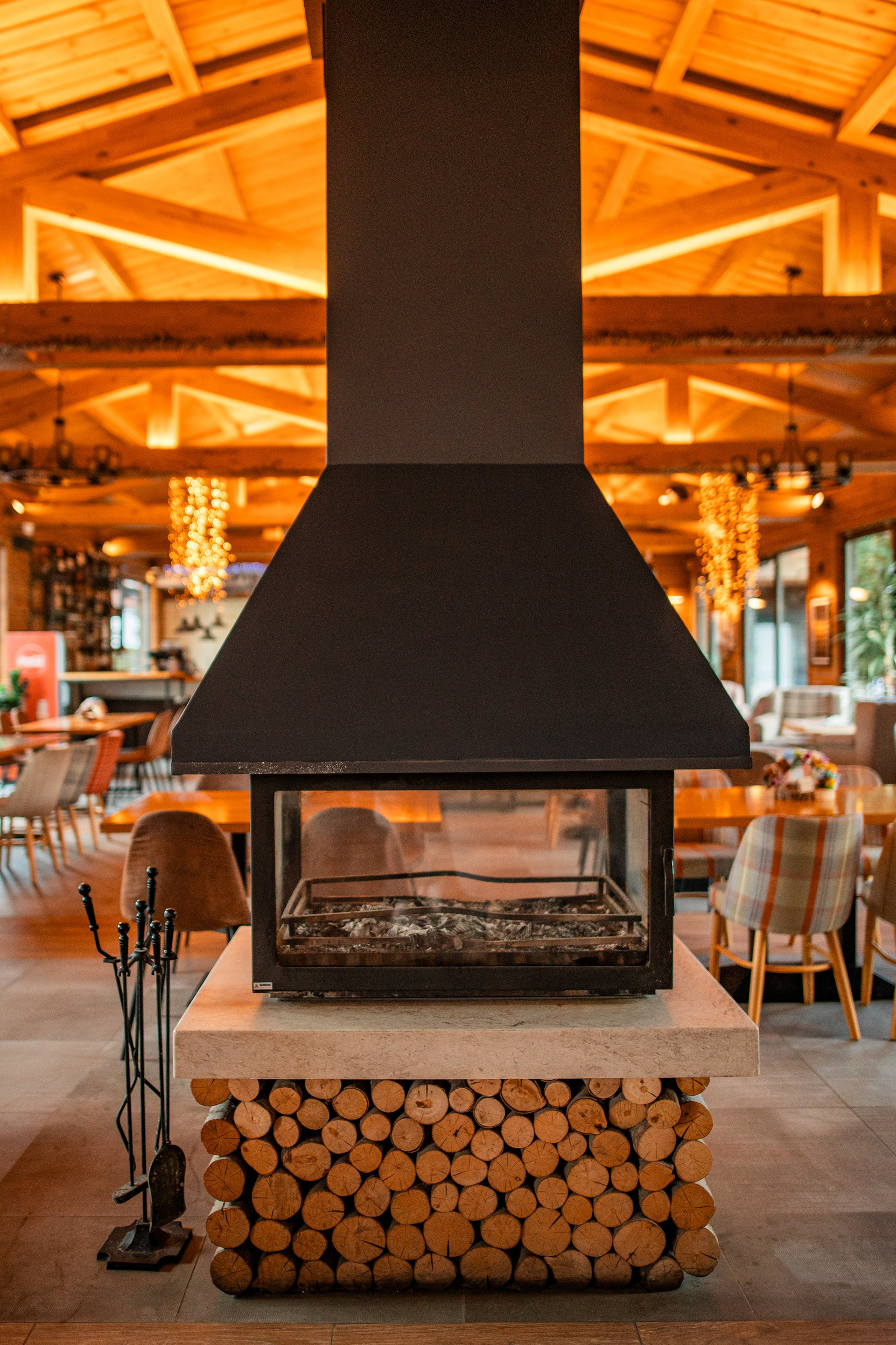 A cozy, beautifully designed restaurant with a central fireplace, natural materials, and warm ambience — perfect for relaxing after a day in the mountains.