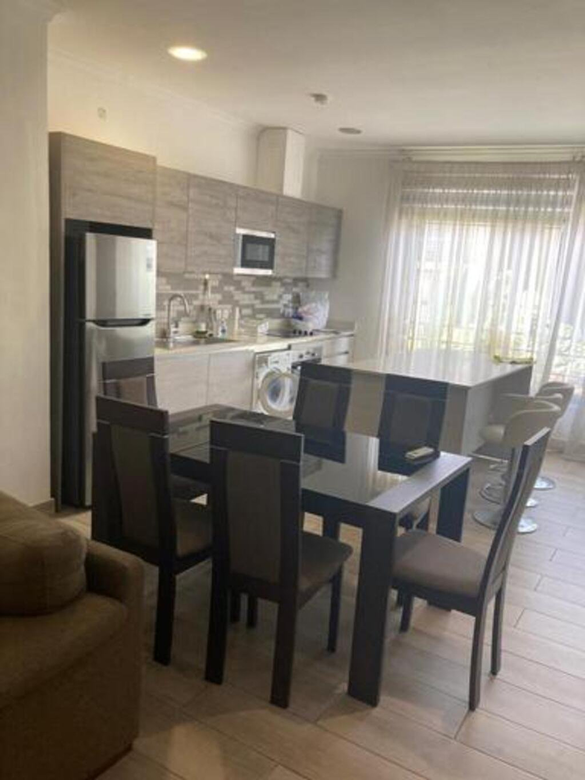 Dining Area The dining area is neatly arranged with a stylish high dining table and chairs, offering a perfect space for meals and casual dining. It blends seamlessly with the living area, giving the apartment an open and modern feel.