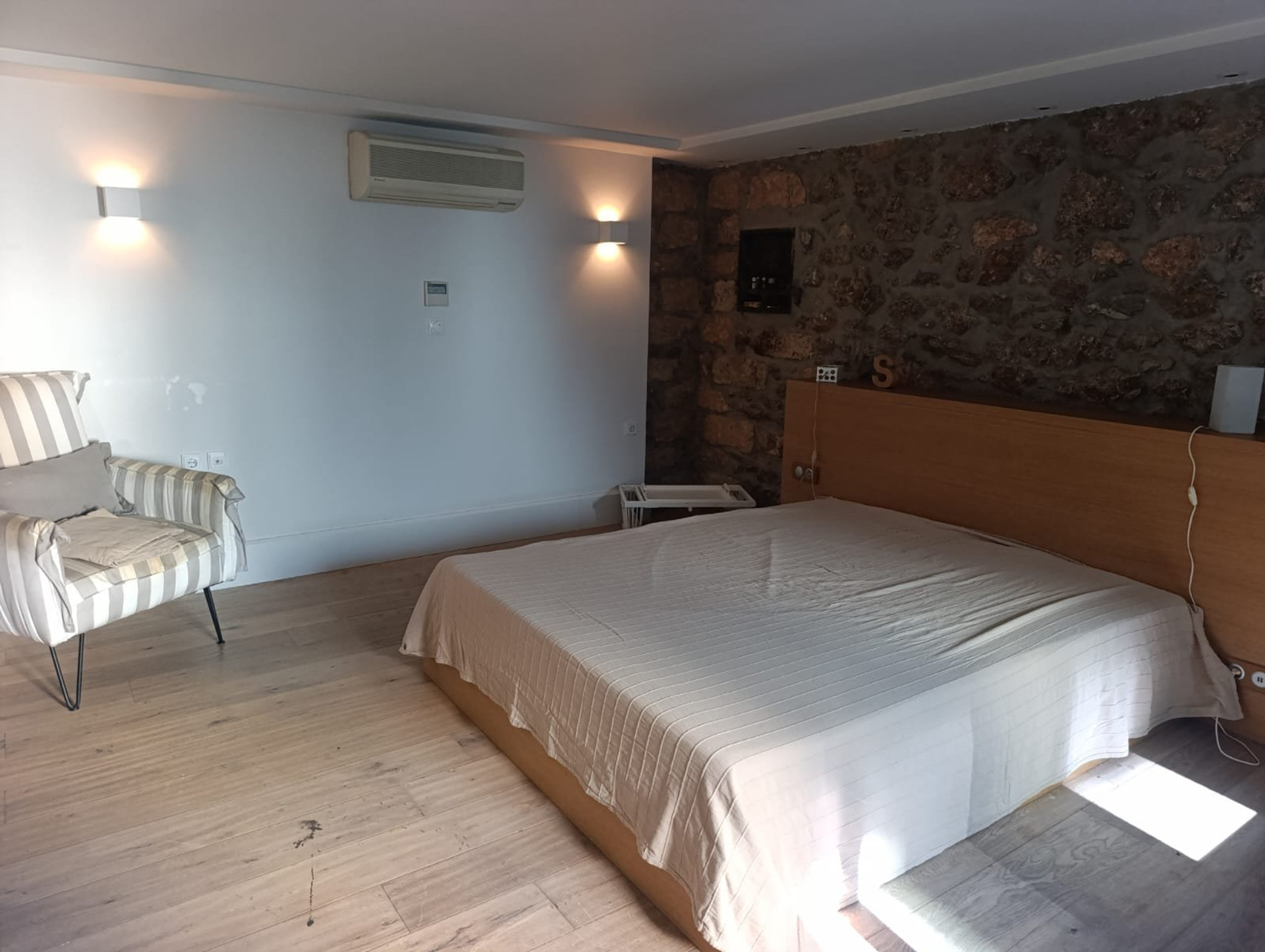 Bedroom with armchair and stone wall