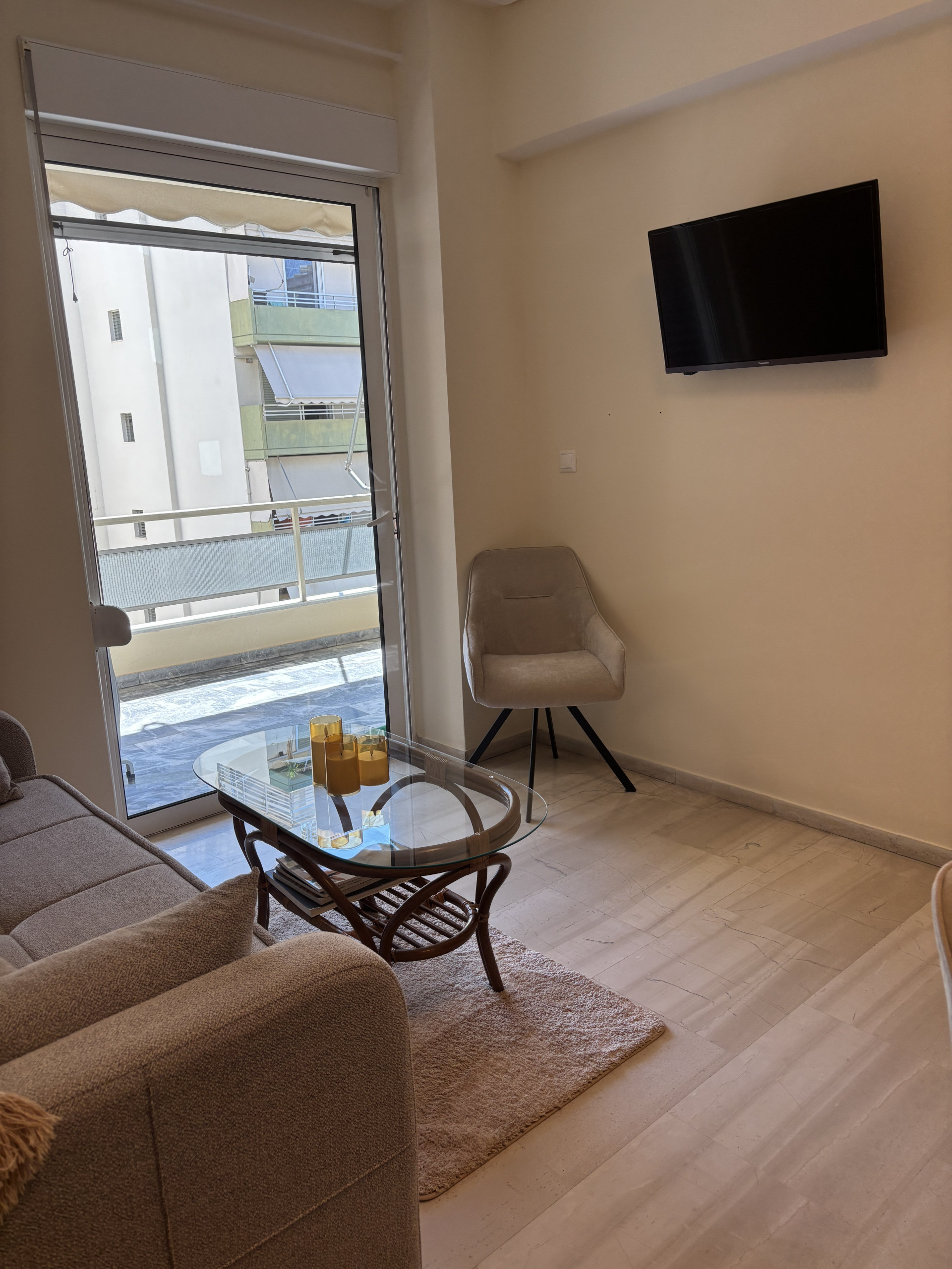 Unwind in front of the wall-mounted flat-screen TV, visible right from the sofa. The large glass sliding door opens up to your private balcony, bringing the outdoors in.