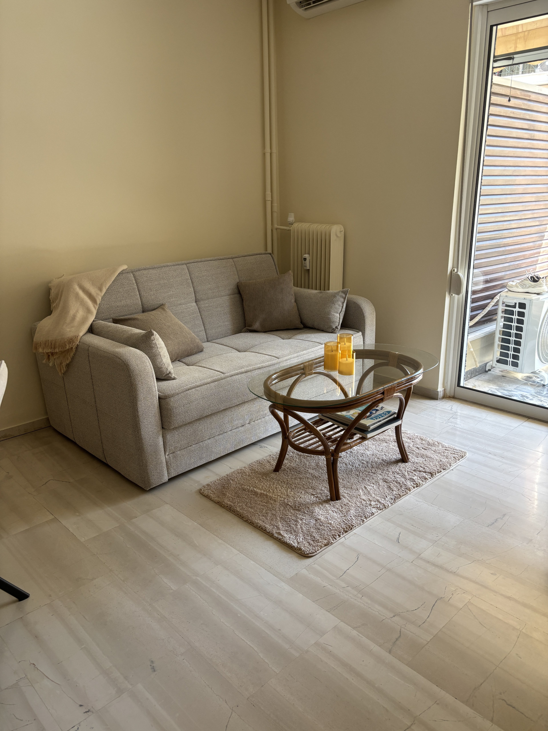 Relax on the cozy fabric sofa, paired with a classic rattan-and-glass coffee table and a soft accent rug. Right next to the balcony door, it gets lovely natural light.