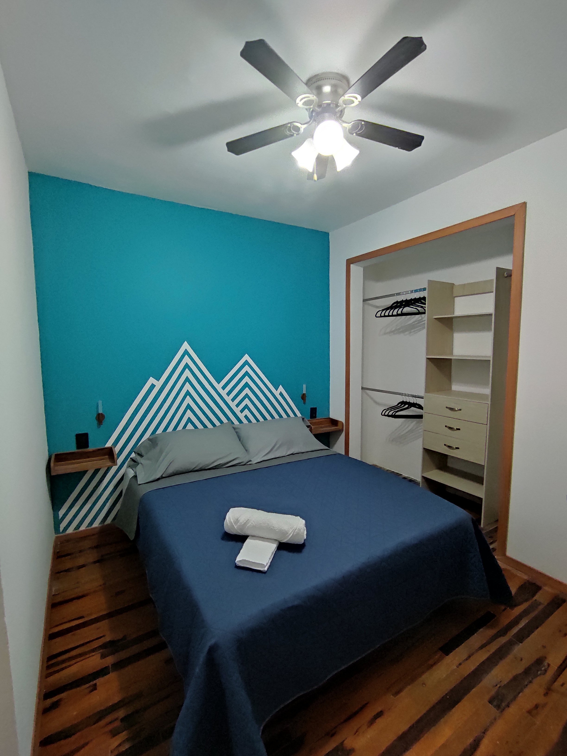 Your queen-size bed and closet with a ceiling fan.