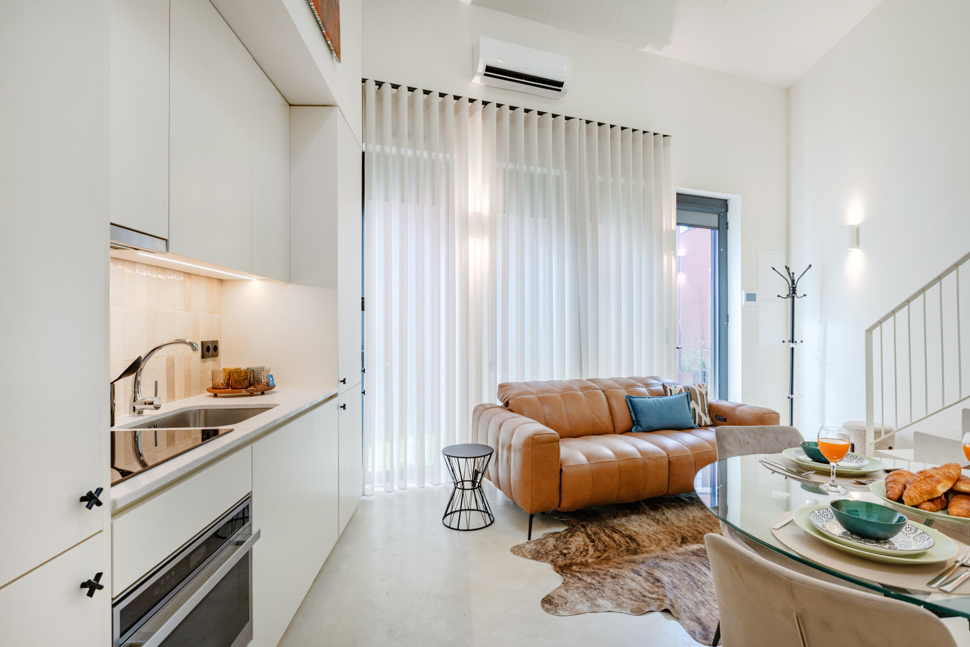 Living area with a leather sofa, TV, kitchenette, and dining table.