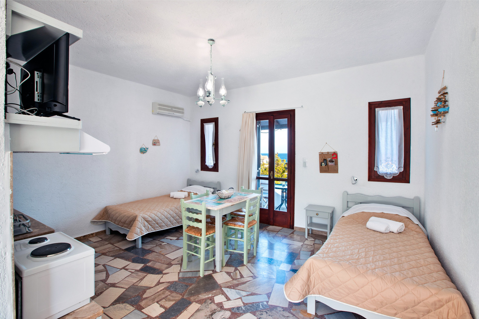View of the living room with two single beds, table with chairs, part of the kitchenette and entrance to balcony