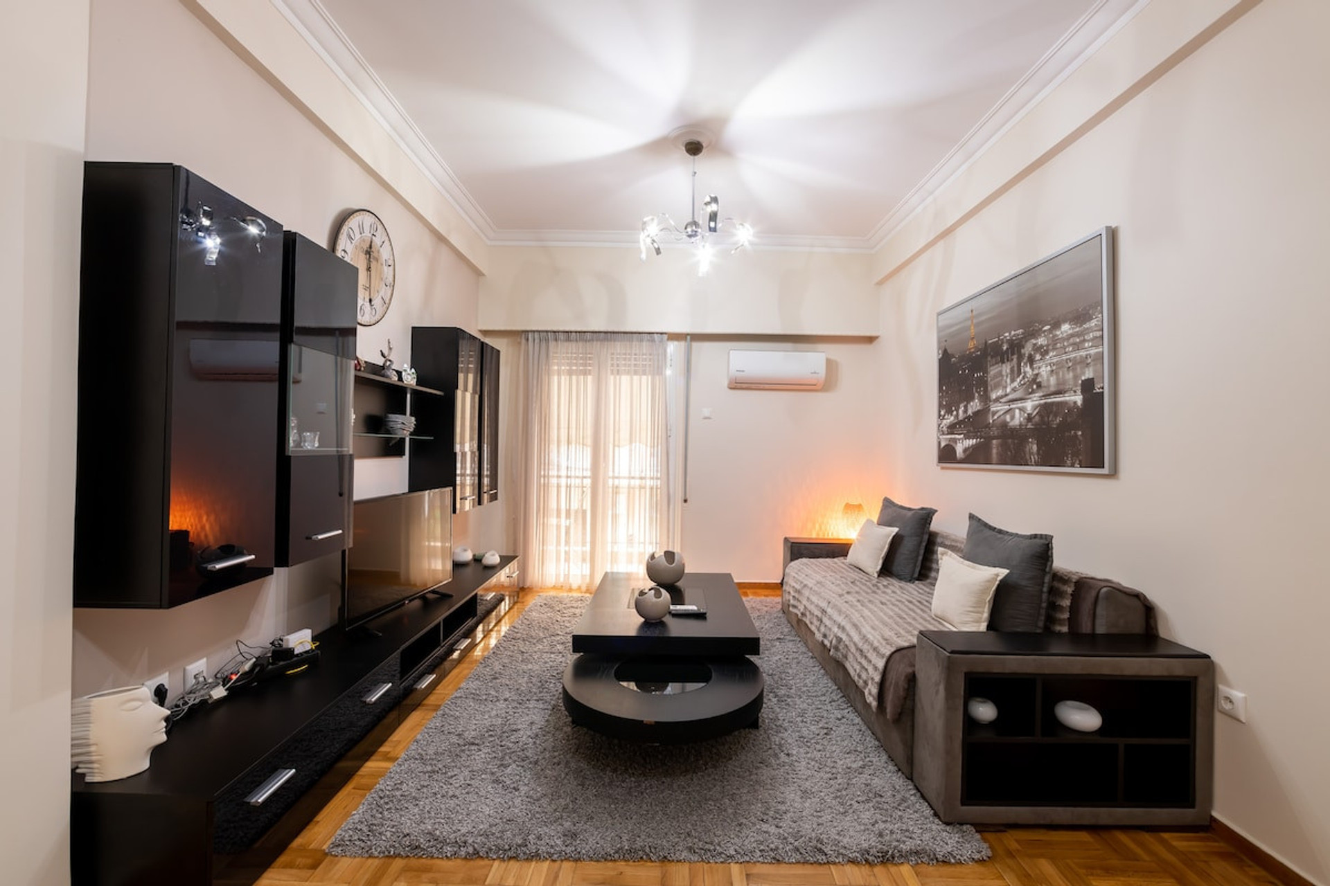 Bright and inviting living room featuring modern furnishings, a cosy sofa, sleek black entertainment unit, and tasteful decor. Natural light streams through large windows, creating a warm and relaxing atmosphere perfect for unwinding.