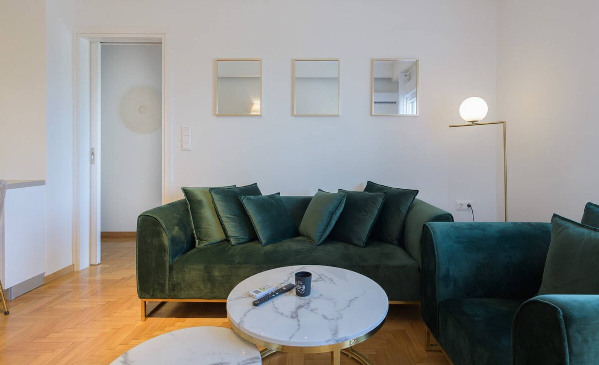 Elegant and cosy living room featuring plush green velvet sofas, a sleek marble coffee table, and warm ambient lighting. A perfect space to relax and unwind in style.