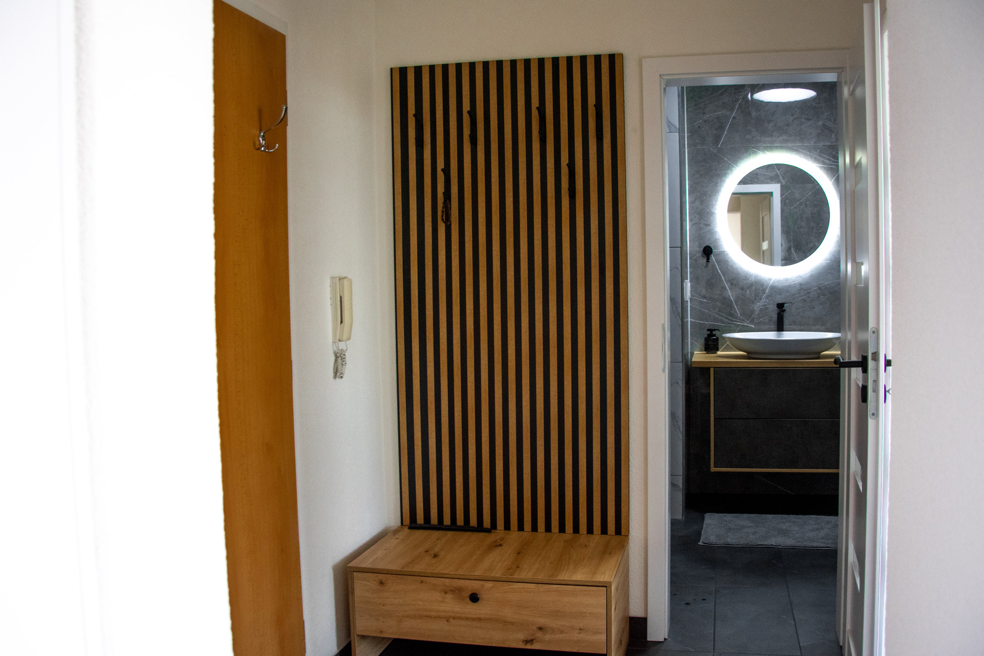 Entryway with wooden panel and bathroom