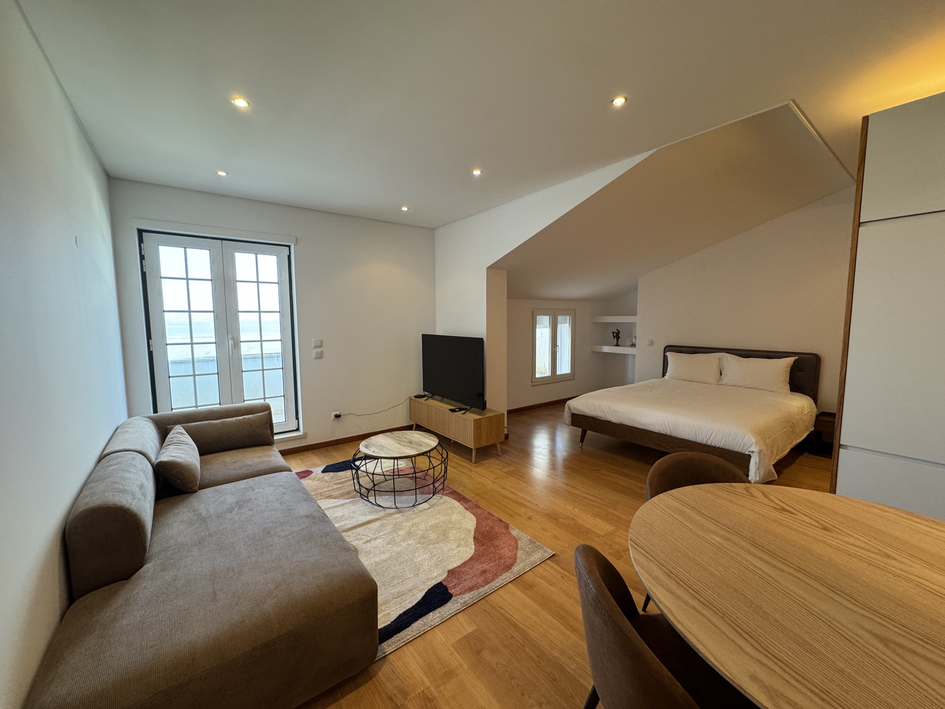 Open-plan studio with sofa, TV and queen-size bed