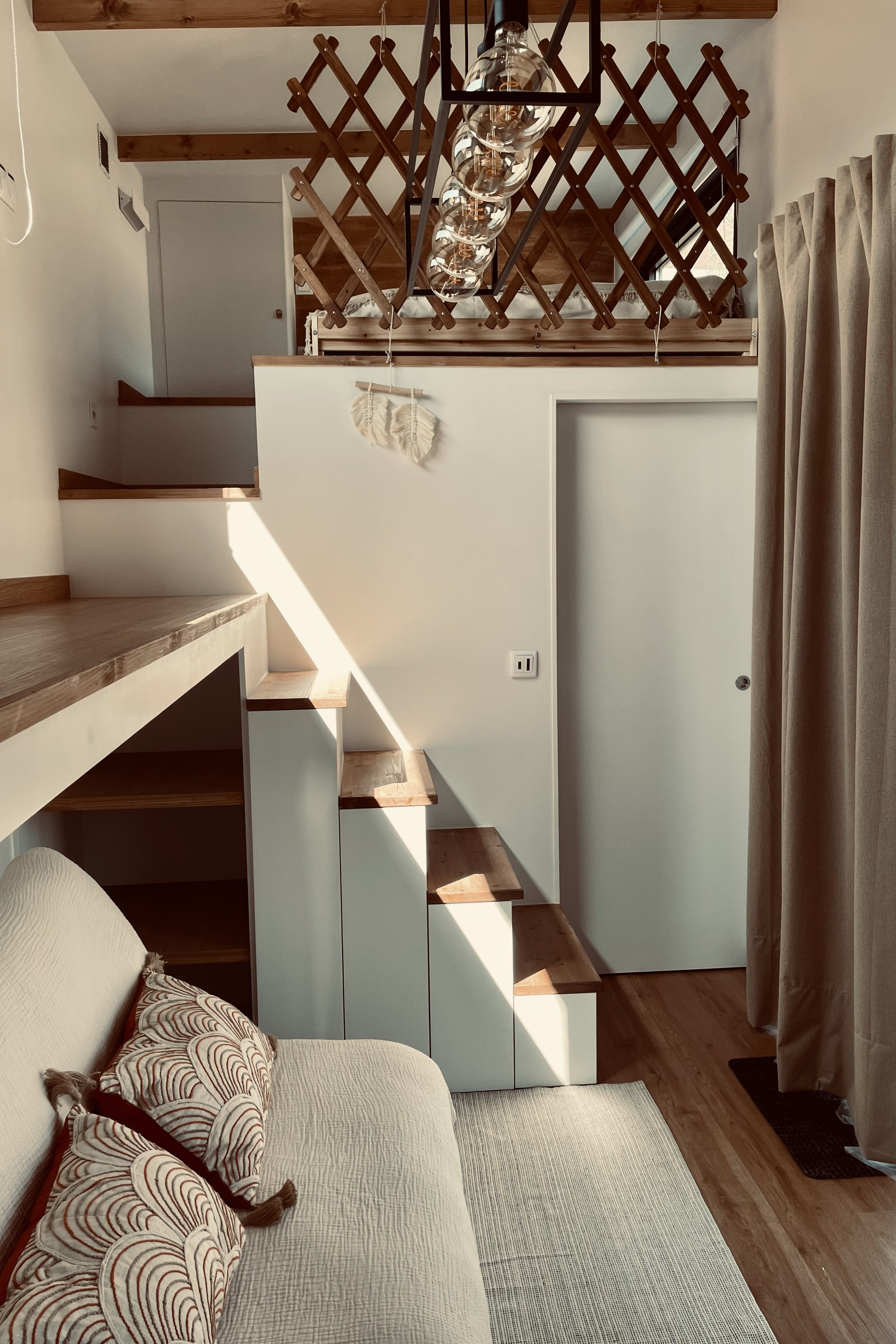 Living room with stairs to the mezzanine bedrooms and door to the bathroom