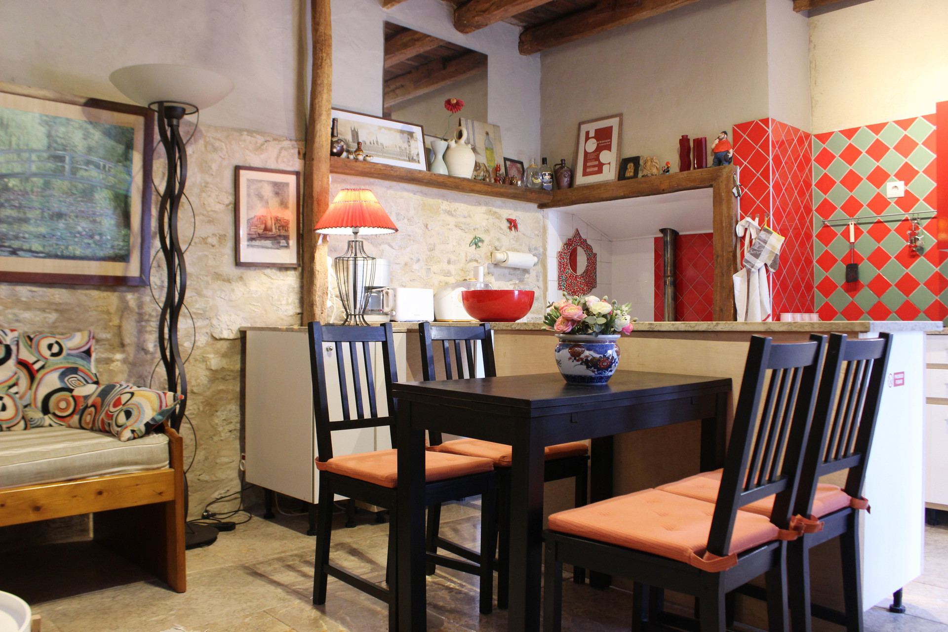 Dining area with colorful kitchen beyond