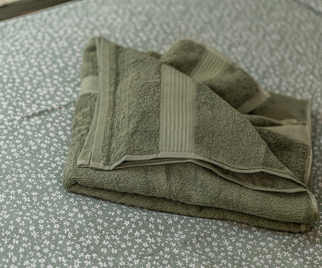 Folded green towel on bed
