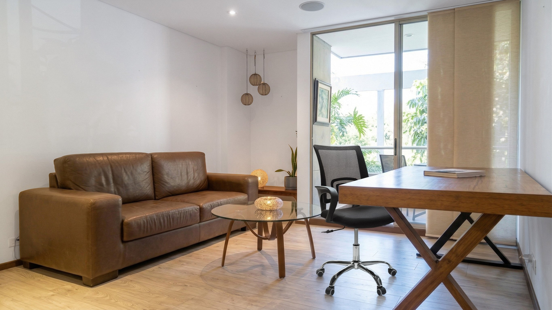 Bright living area with a comfortable sofa, dedicated work desk and access to the private balcony.