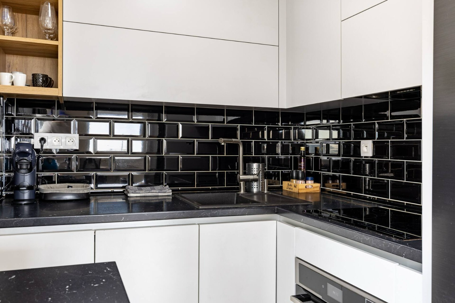 Kitchen with black backsplash and white cabinets