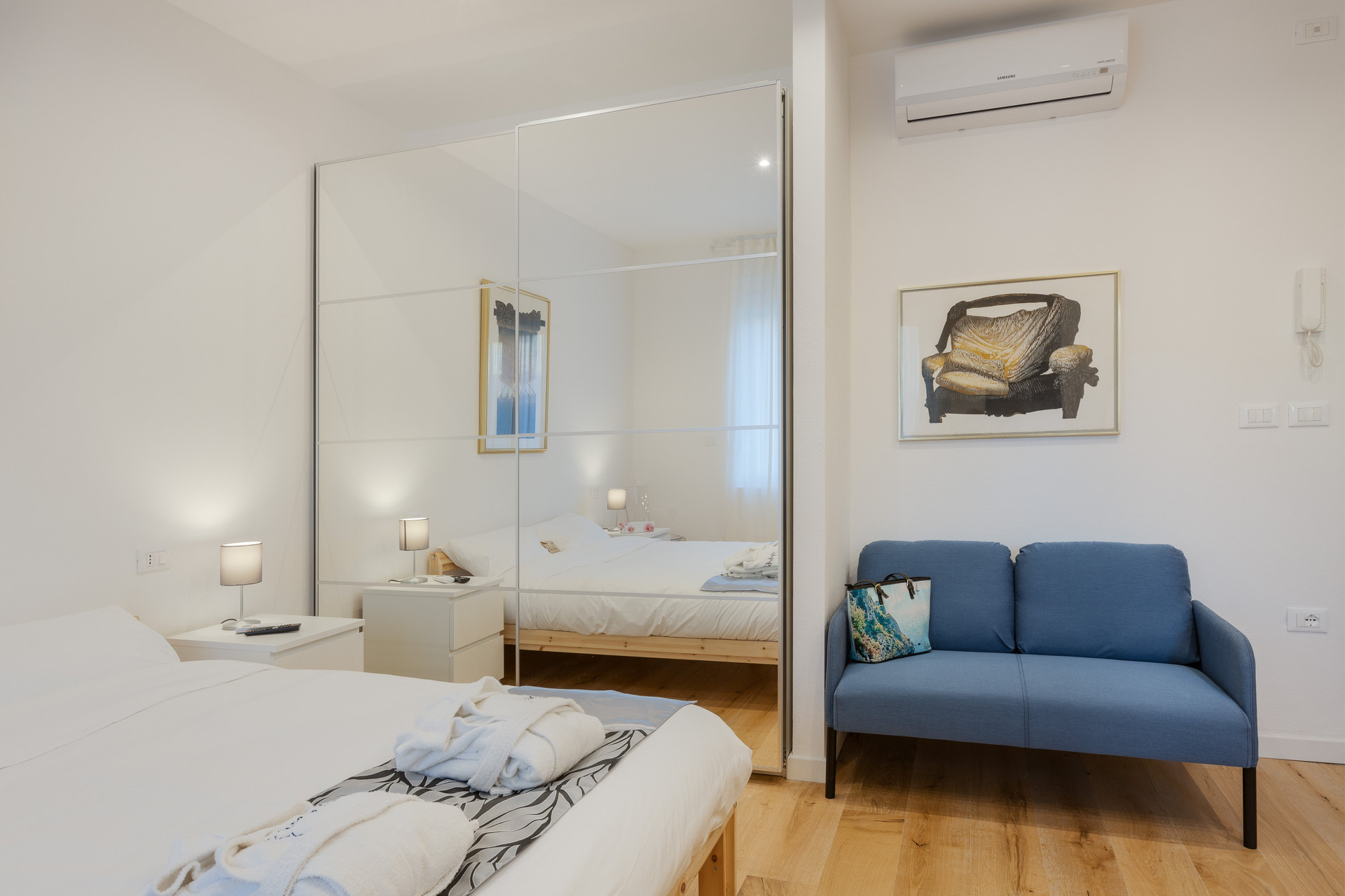 Bedroom with mirrored wardrobe and sofa