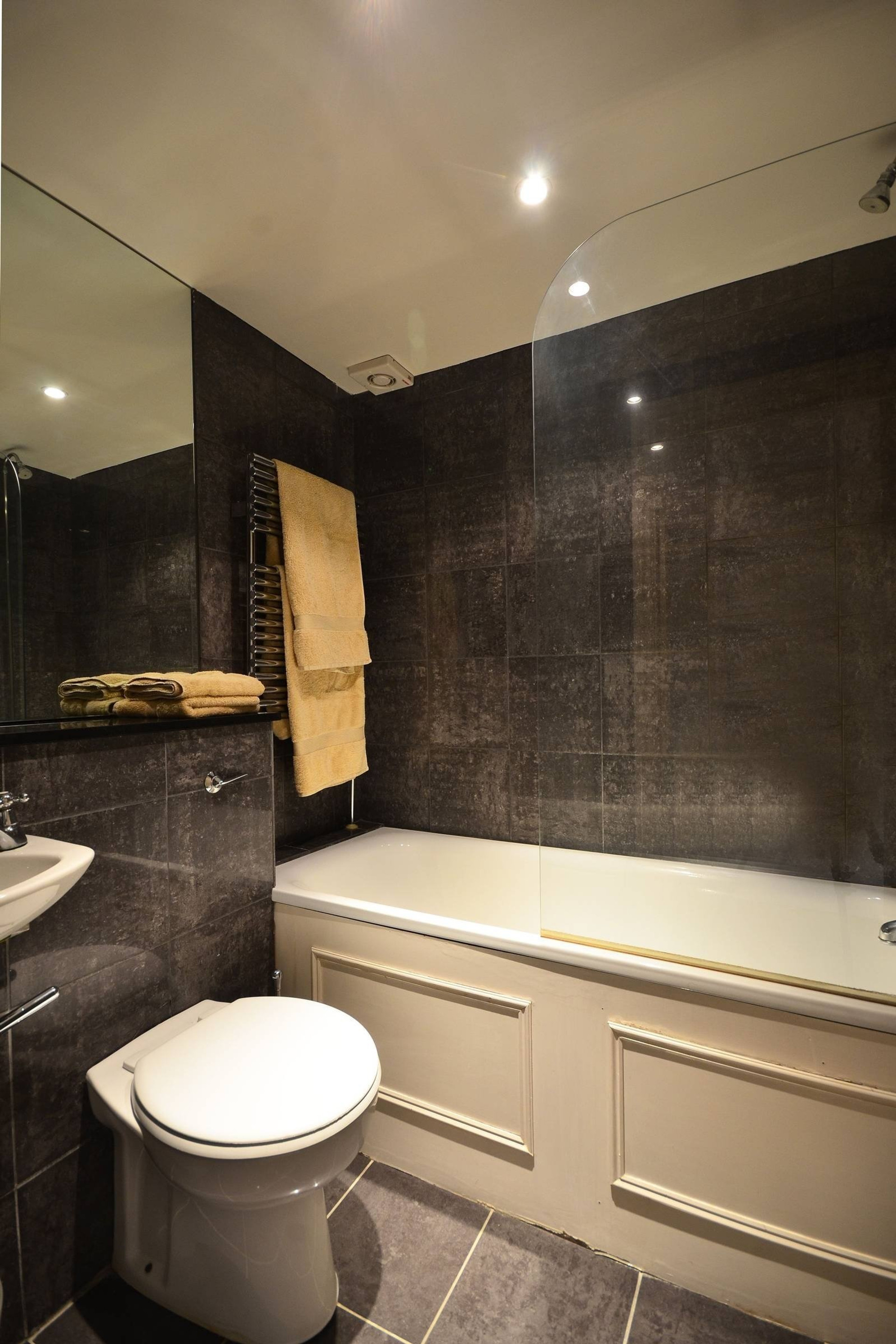Dark tiled bathroom with bathtub